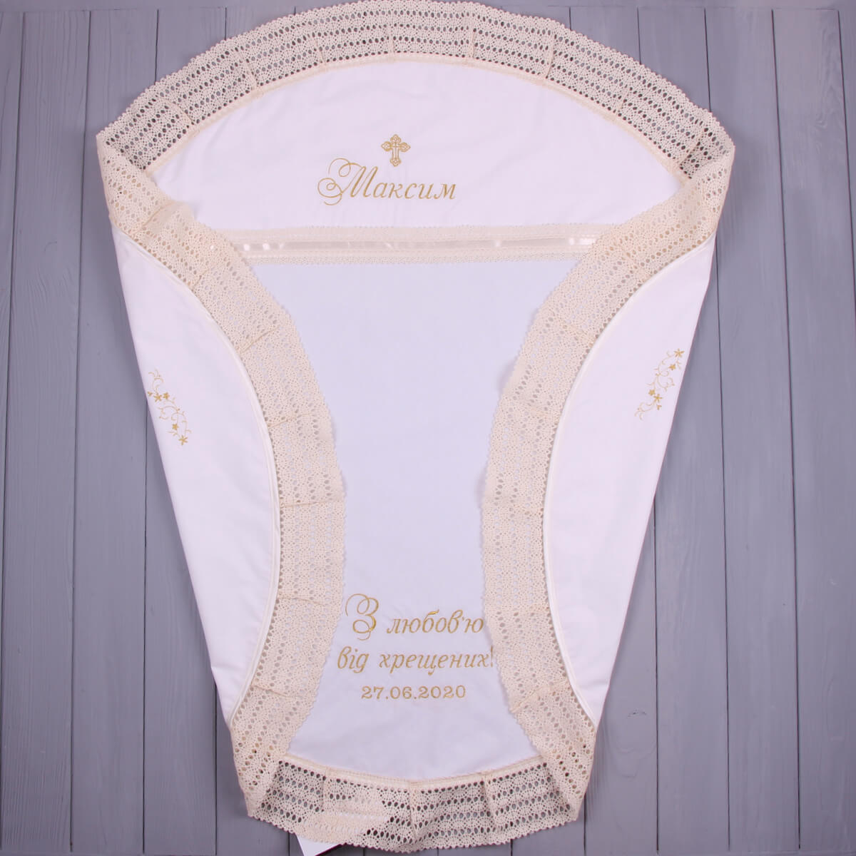 White baby round christening blanket with beige lace trim on a wooden surface