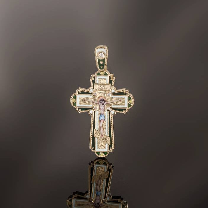 Gold cross pendant with a reflective surface on a dark background