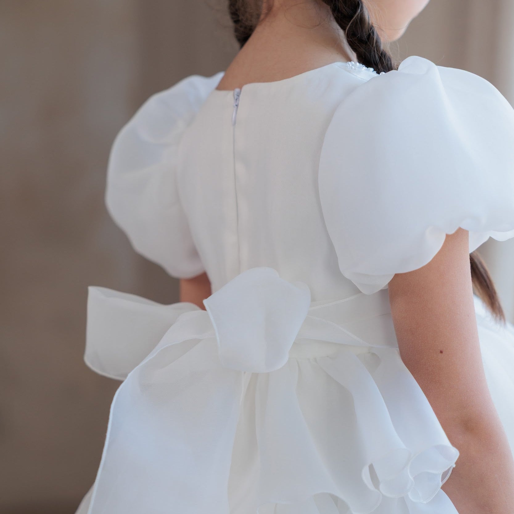 White dress with puffed sleeves and a bow detail on a blurred background