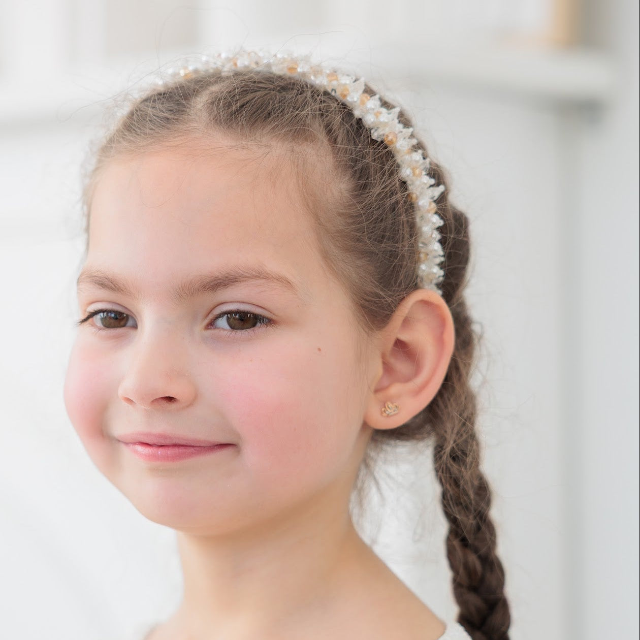 Young girl with braided hair wearing a white top in a blurred indoor setting
