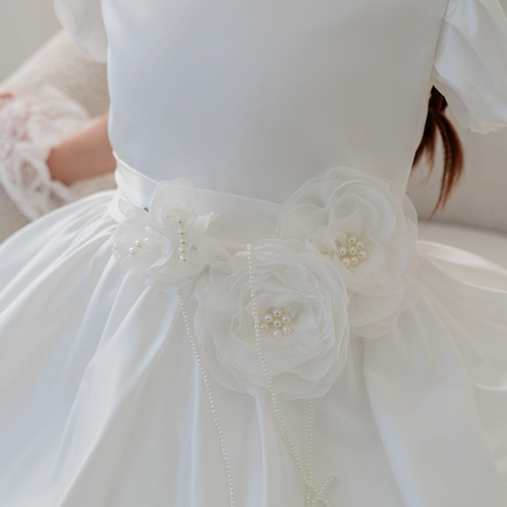 Close-up of a white dress with floral details and lace trim.