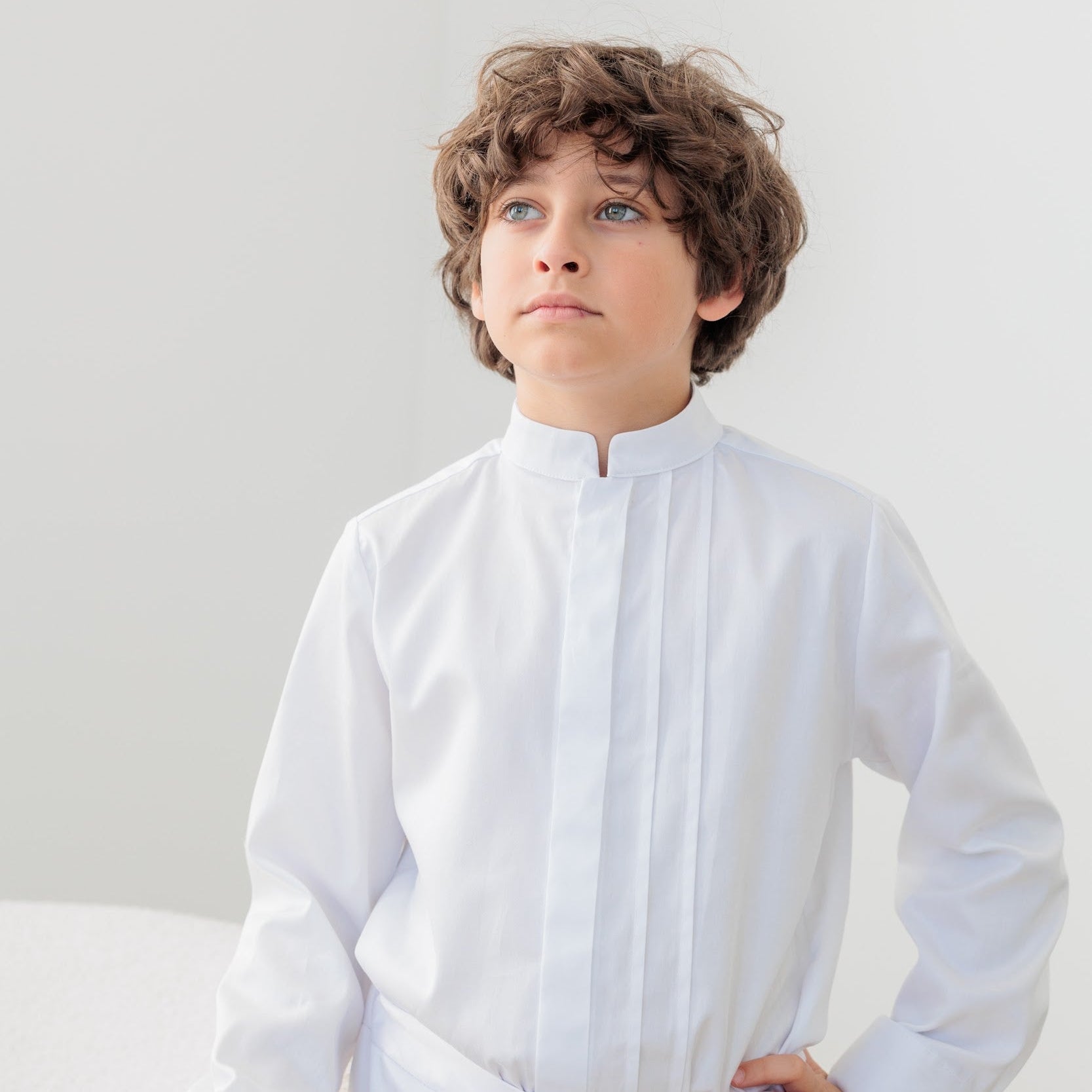 Young boy wearing a white commuion shirt against a plain background