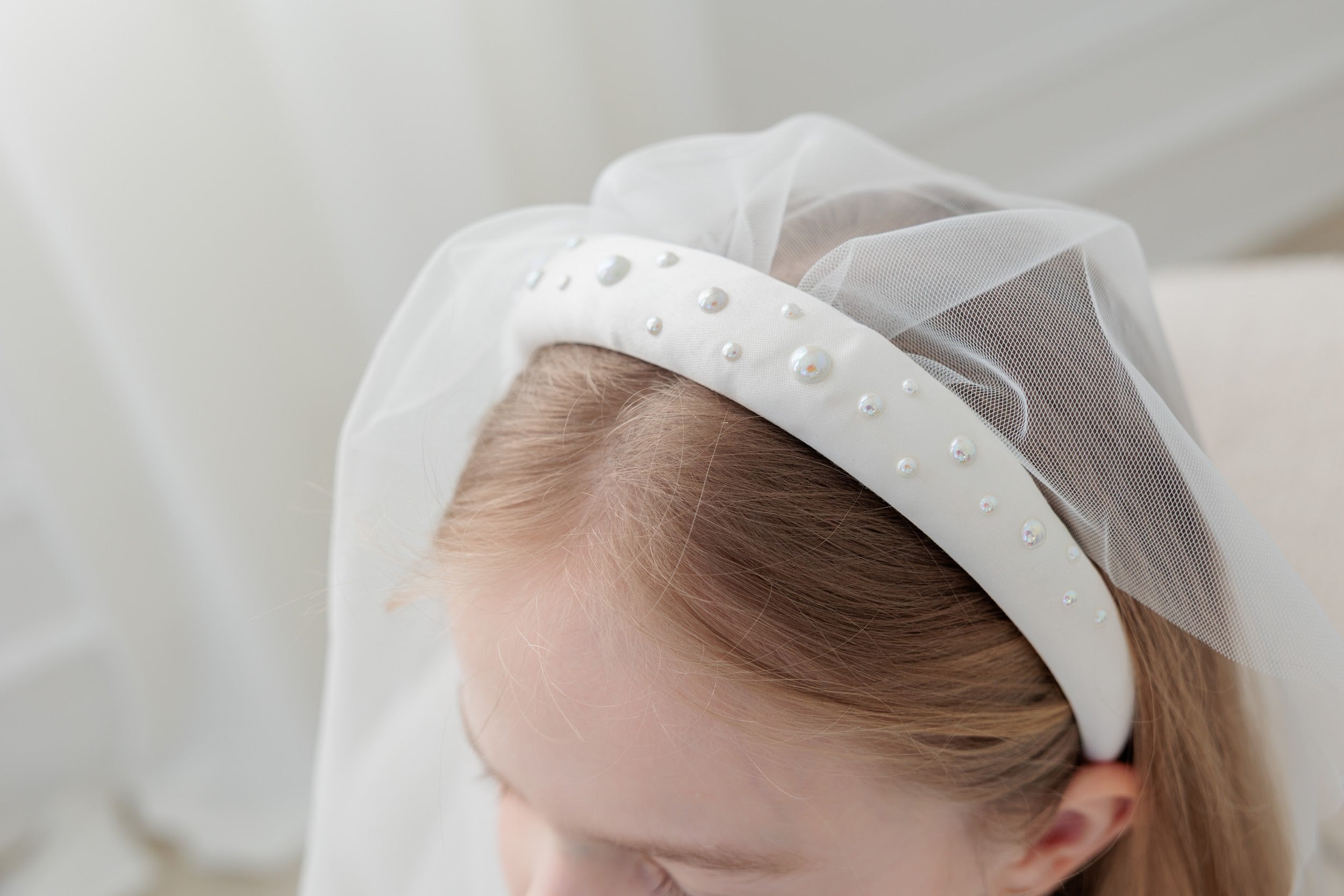 White headband with pearls and tulle on a neutral background