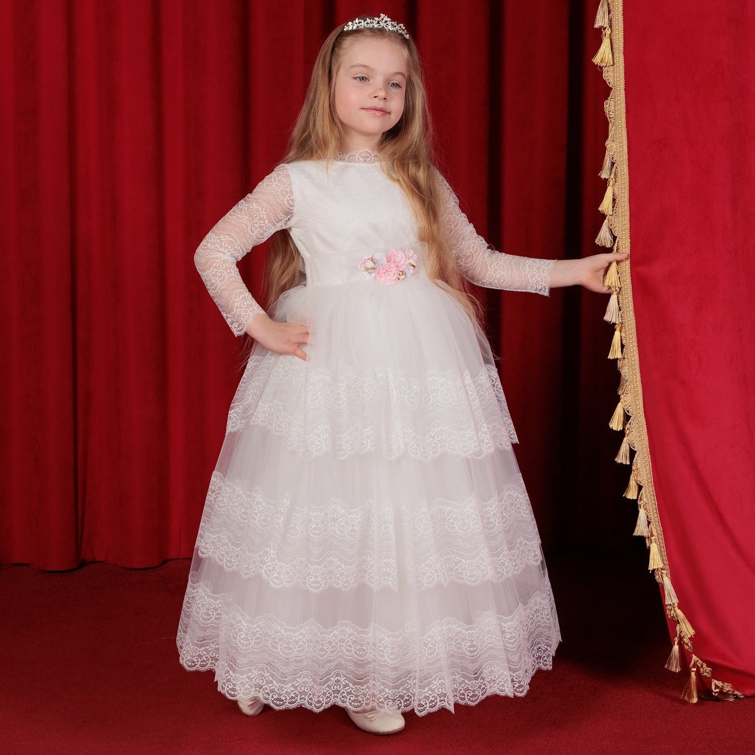 Young girl in a white dress standing in front of red curtains