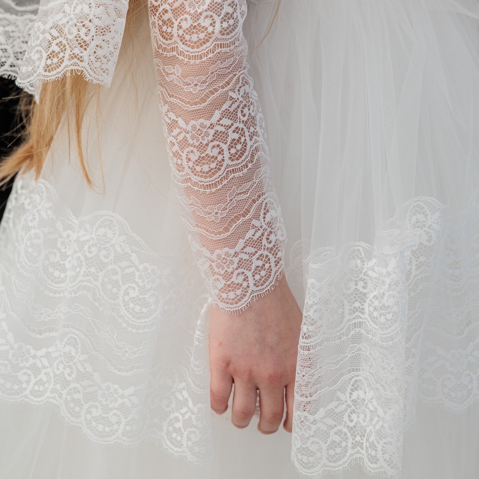 Close-up of a person wearing a white lace wedding dress with a blurred background