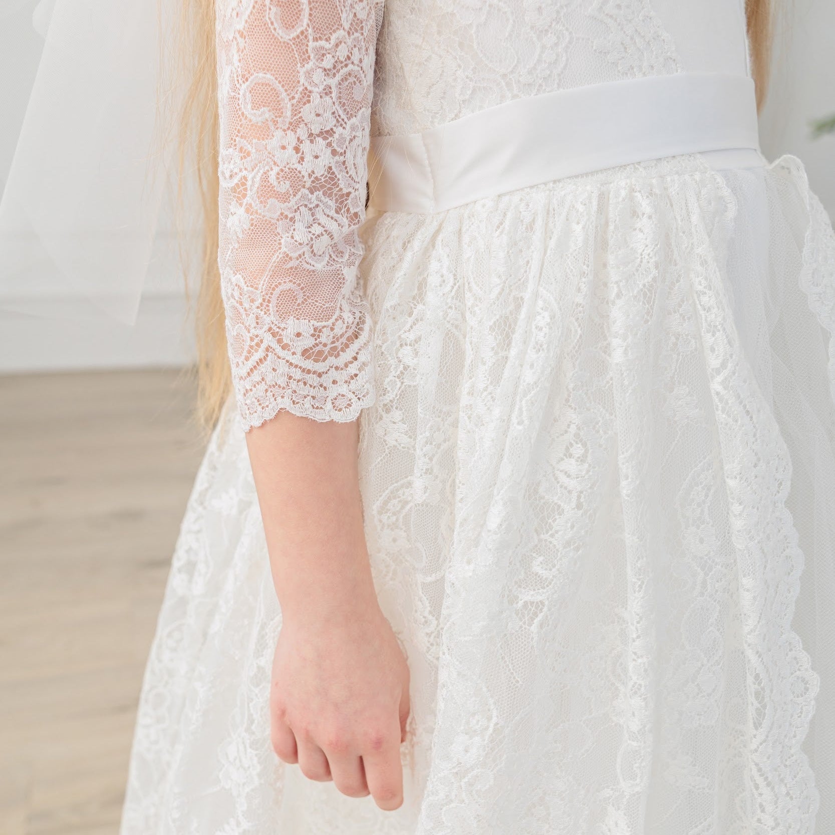 Close-up of a white lace wedding dress with long sleeves.