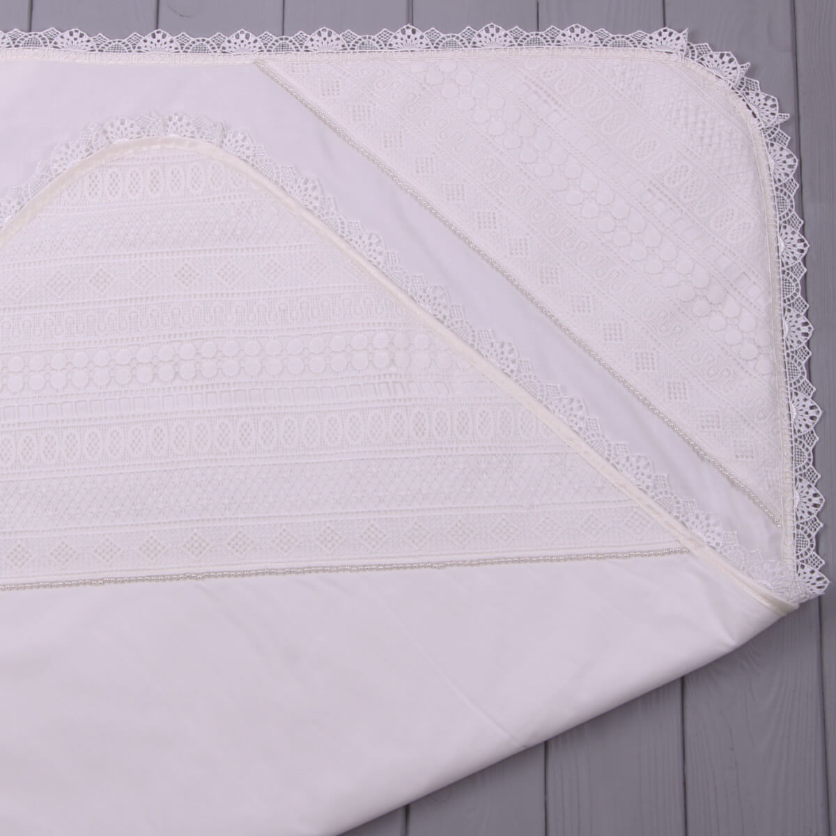 Baptism blanket with lace trim on a wooden surface