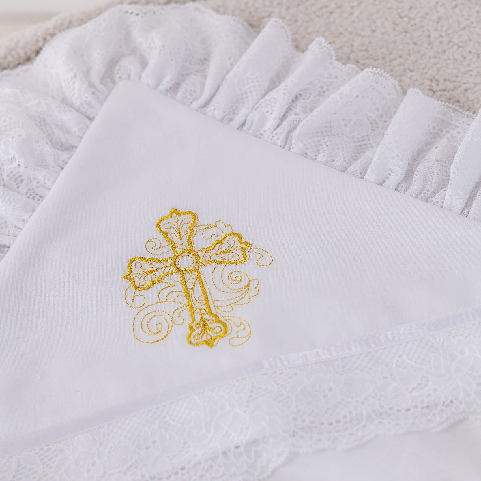 White towel with a gold embroidered cross on a light background