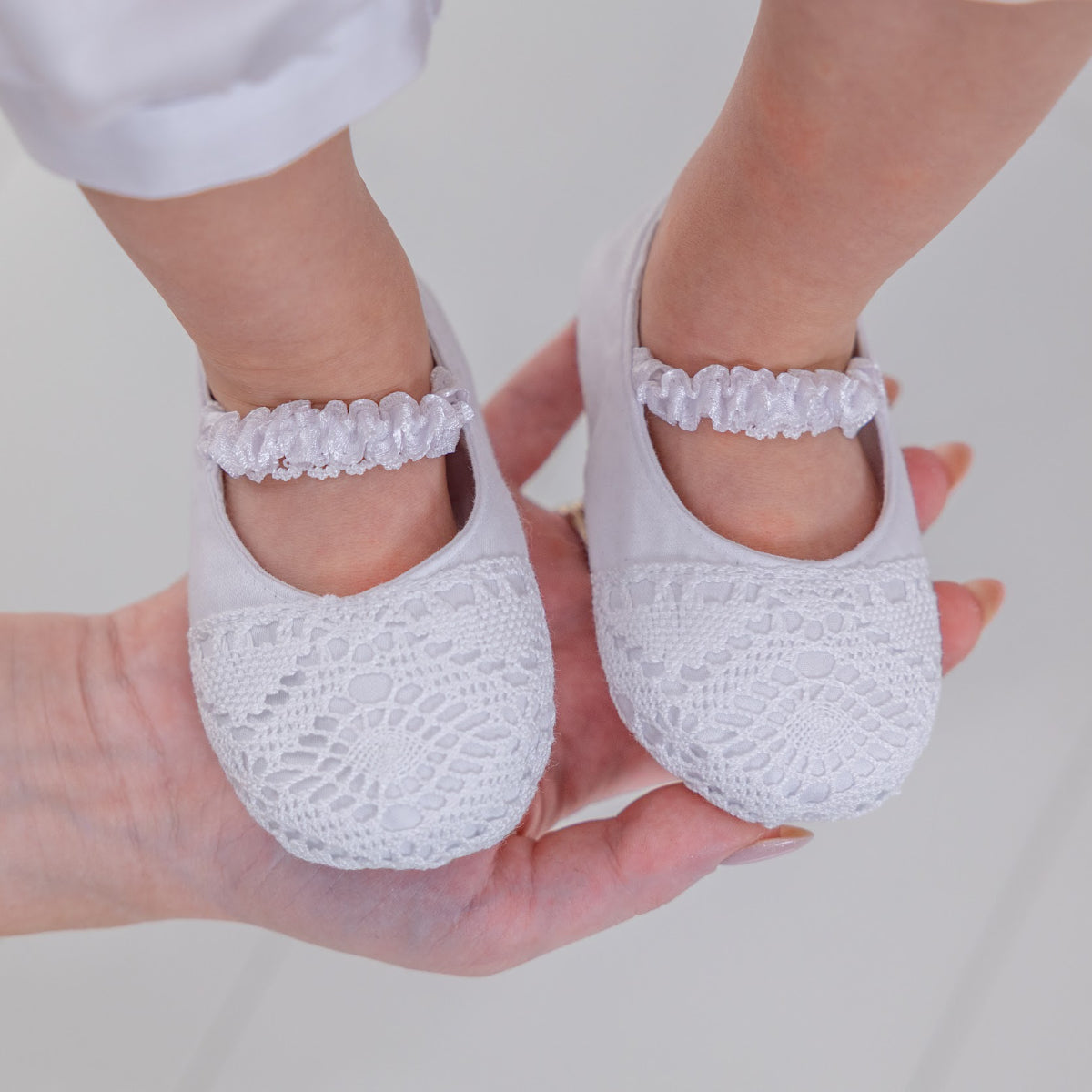 Christening Booties on a white surface with a blurred background