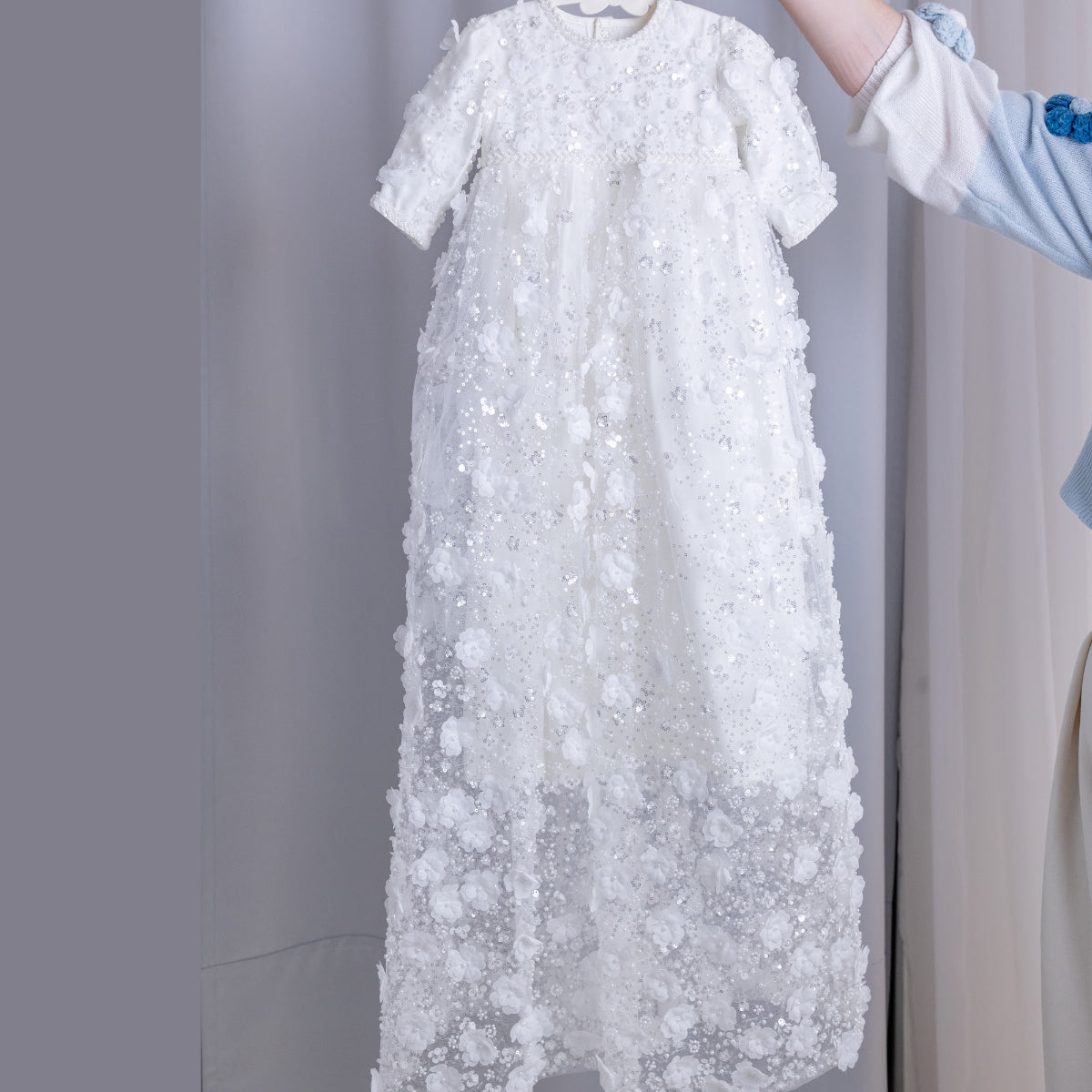 Ivory Christening gown on a hanger against a neutral background