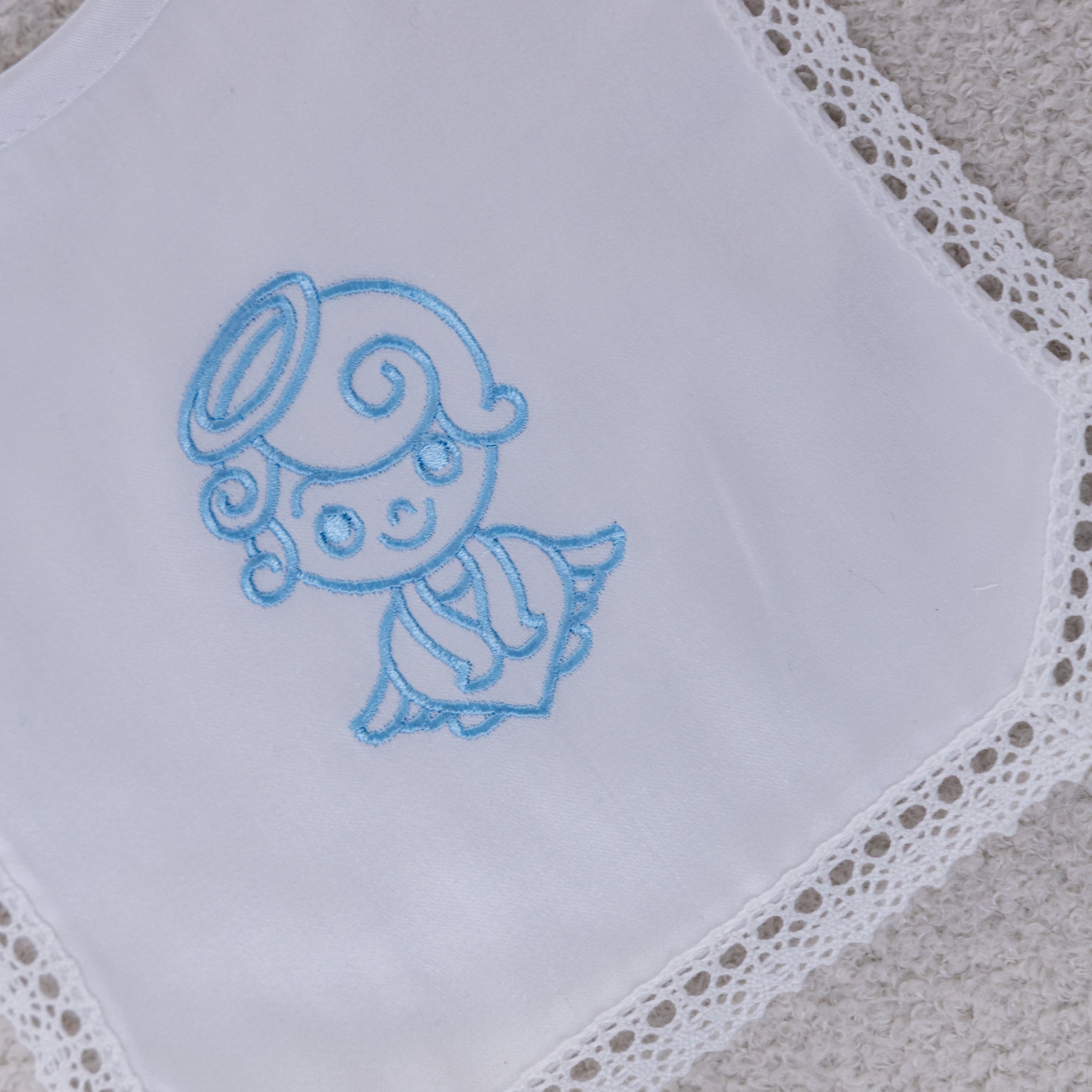 White baby bib with blue embroidered design on a textured surface