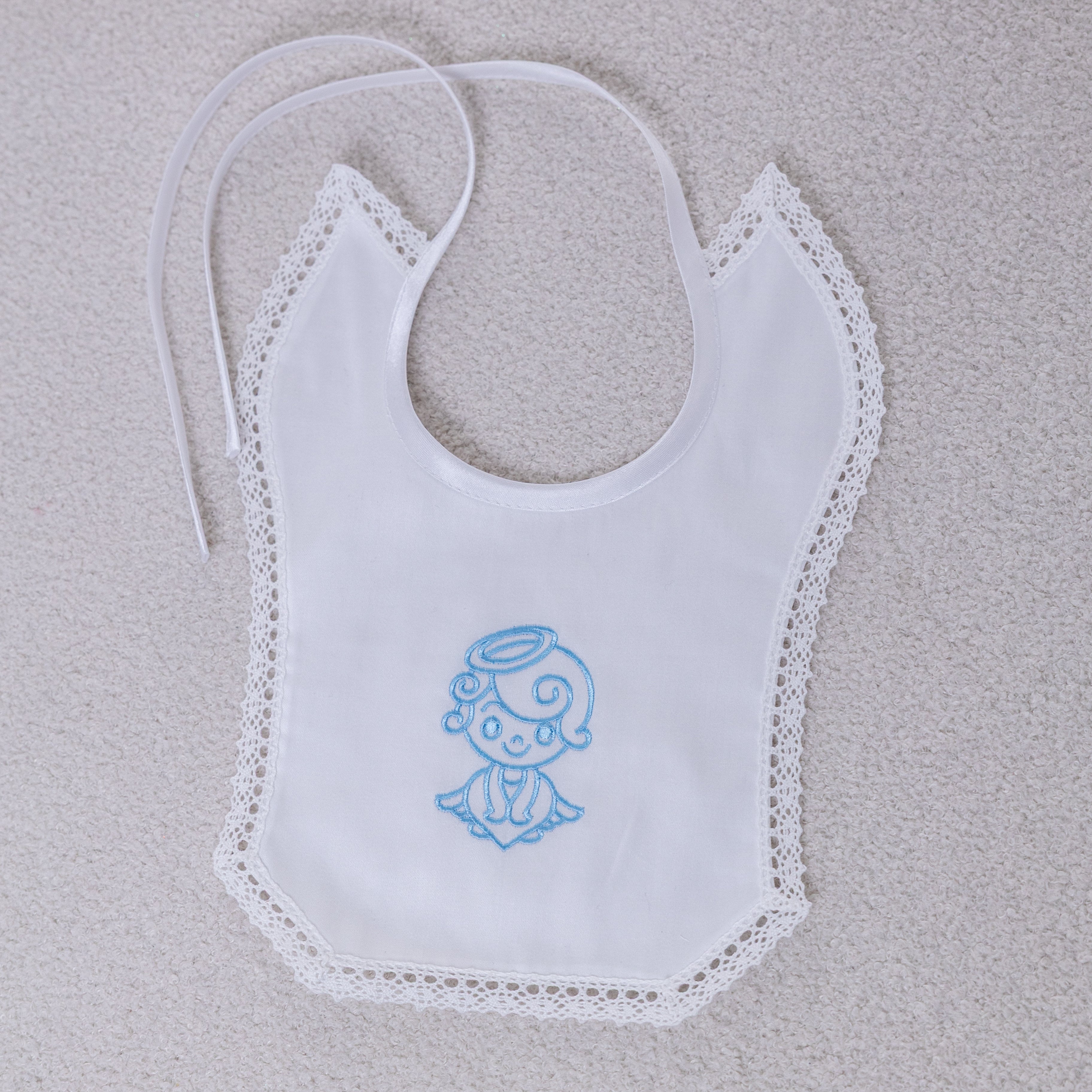 White bib with blue embroidered design on a light gray background