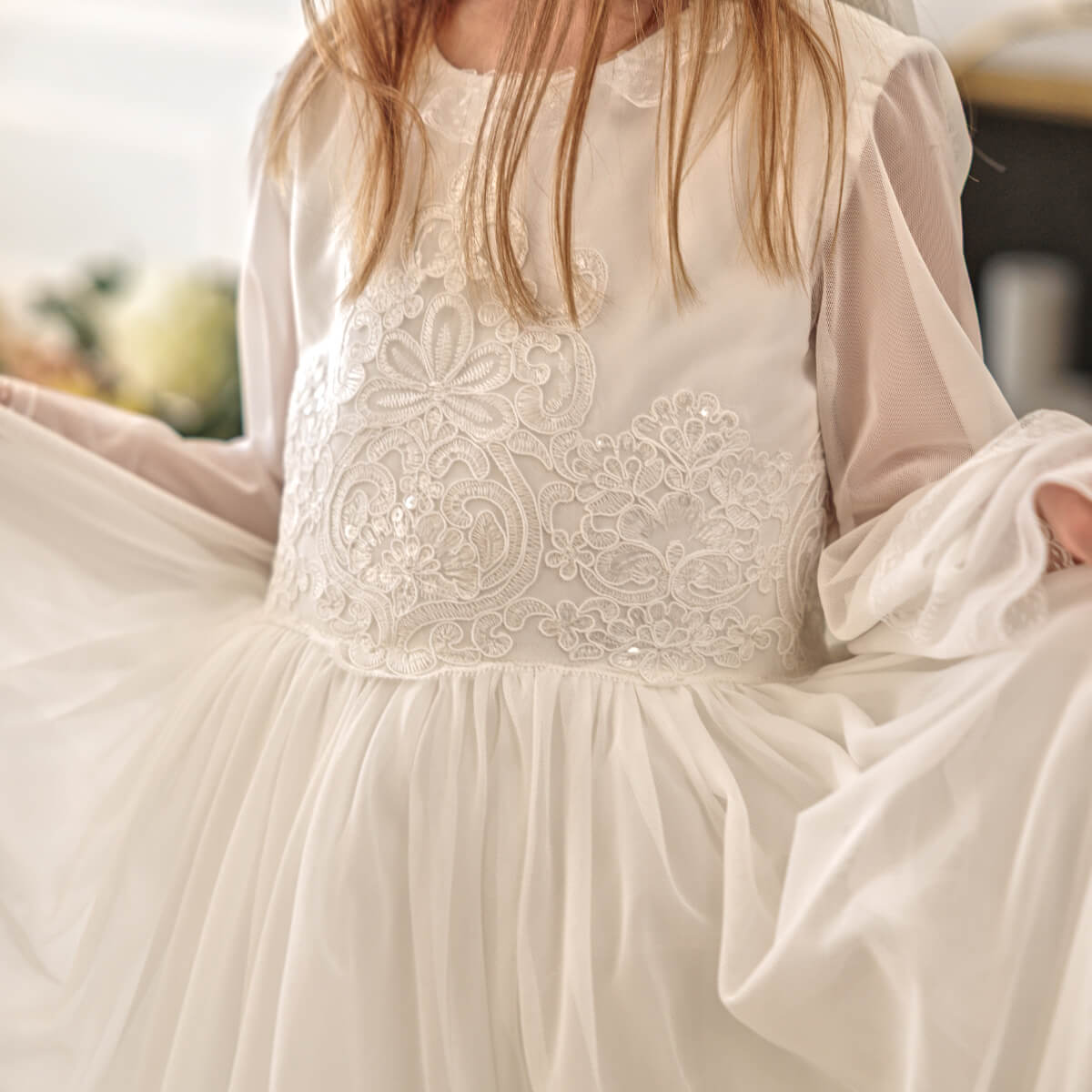 Close-up of a white lace dress with long sleeves and a flowing skirt.