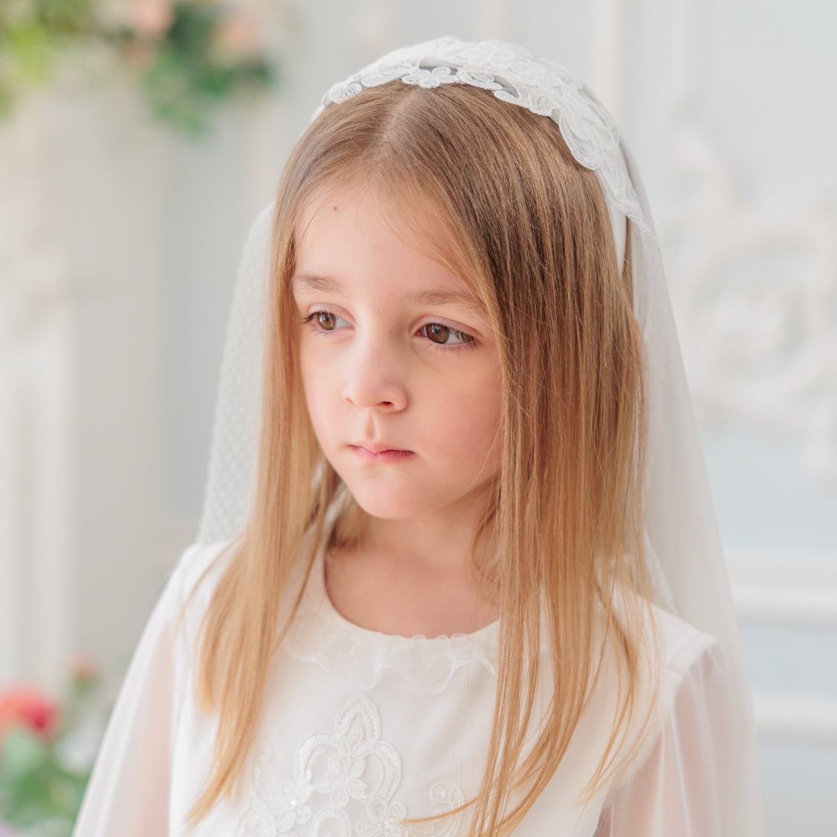 Young girl wearing a white veil in a softly blurred background