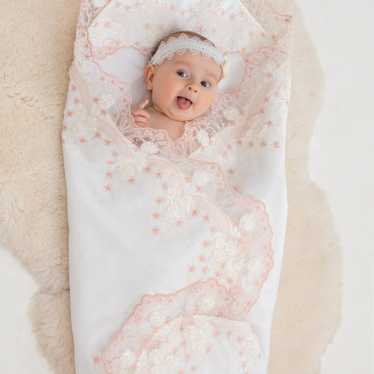 Baby wrapped in a lace blanket on a soft surface