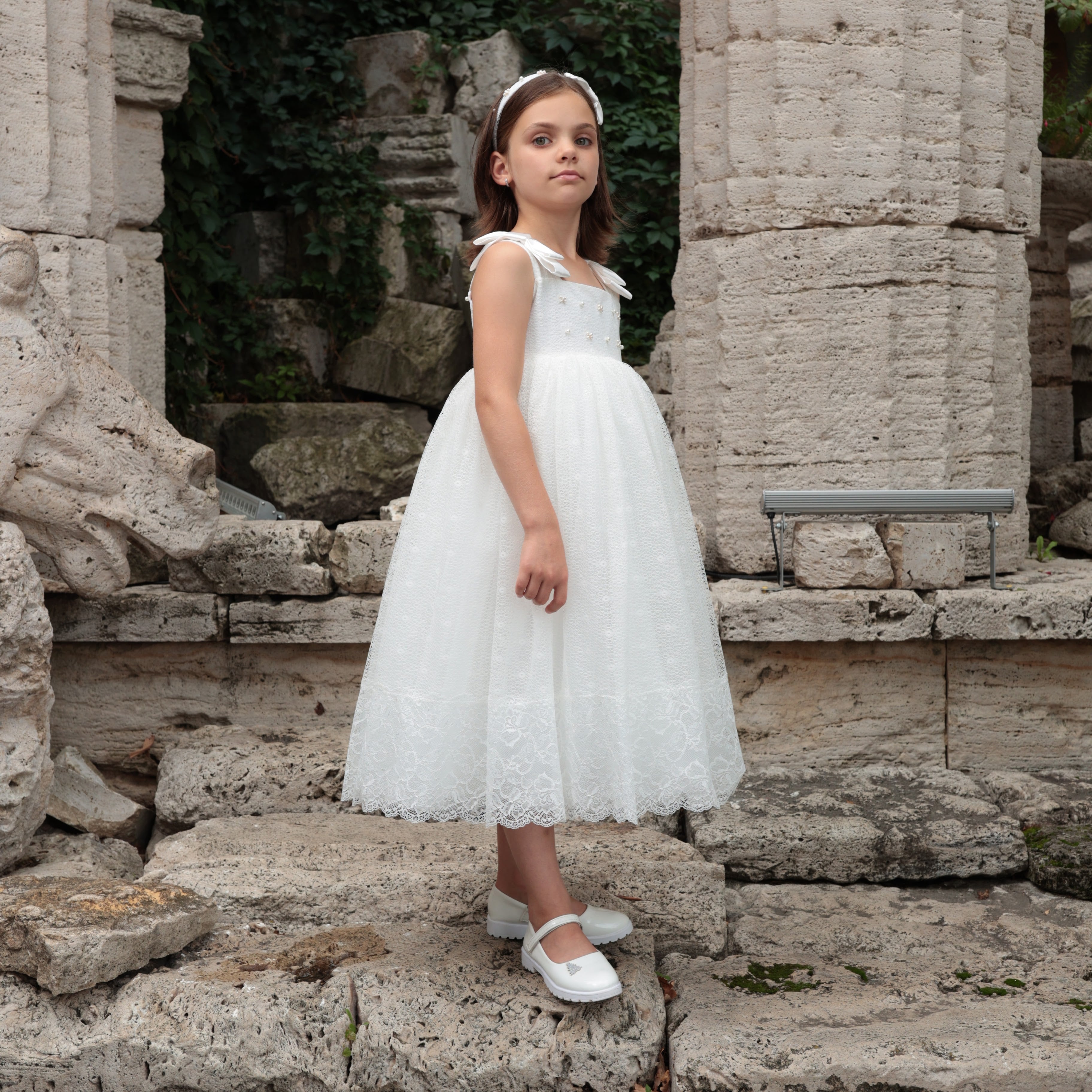 Young girl in a white dress standing among stone ruins