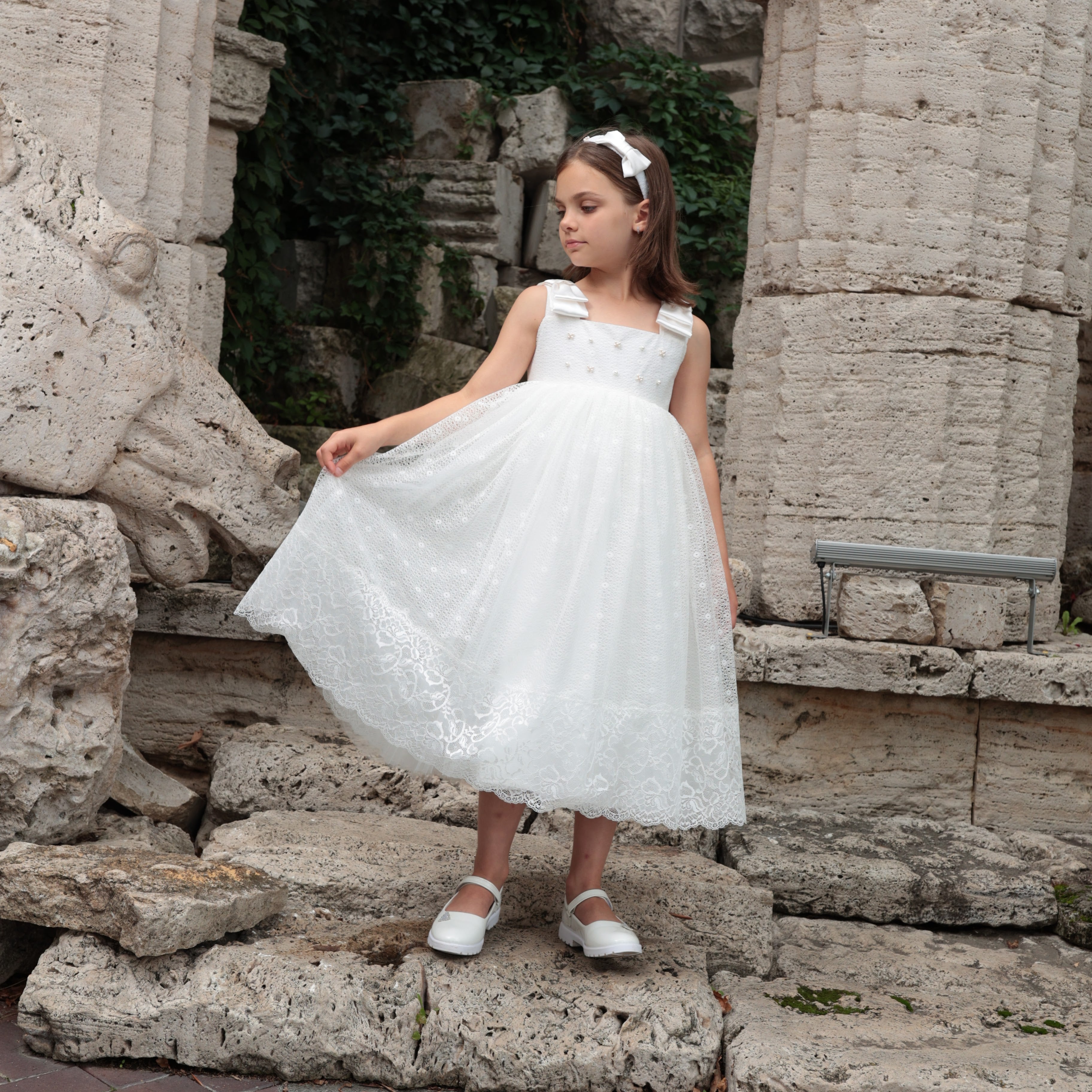 Young girl in a white dress standing on stone ruins