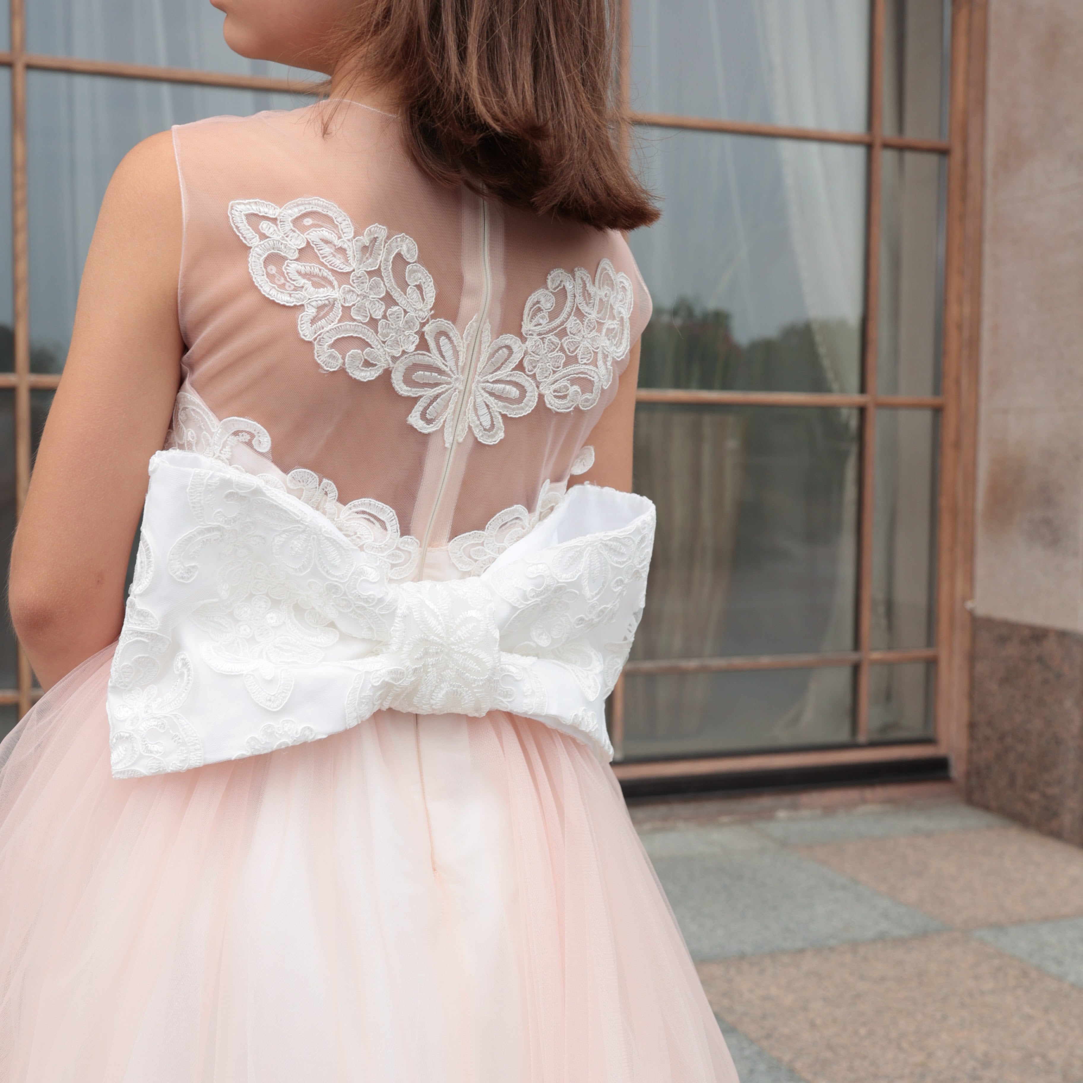 Person wearing a pink dress with lace details in an outdoor setting