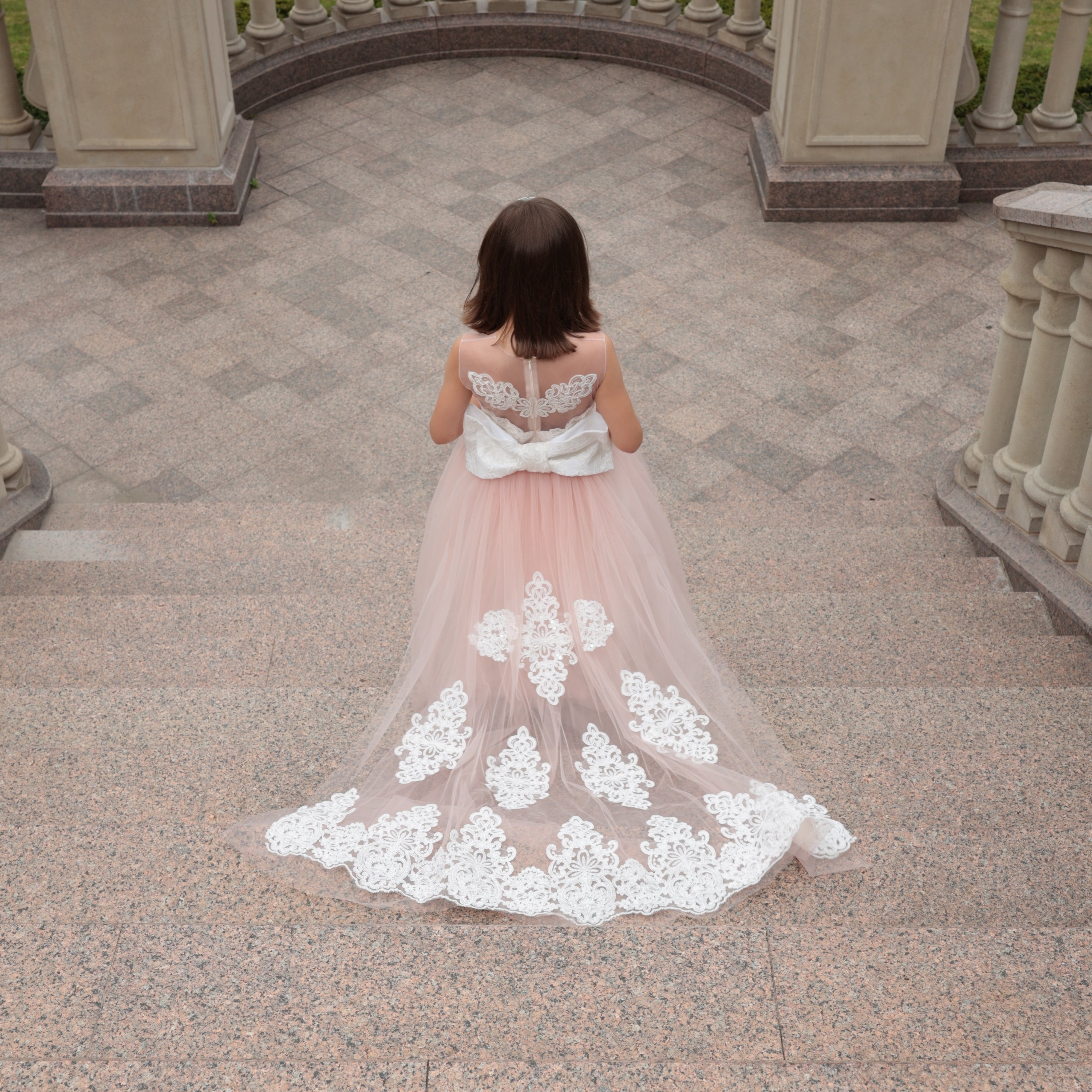 Woman in a floral dress standing in an outdoor setting with classical architecture.