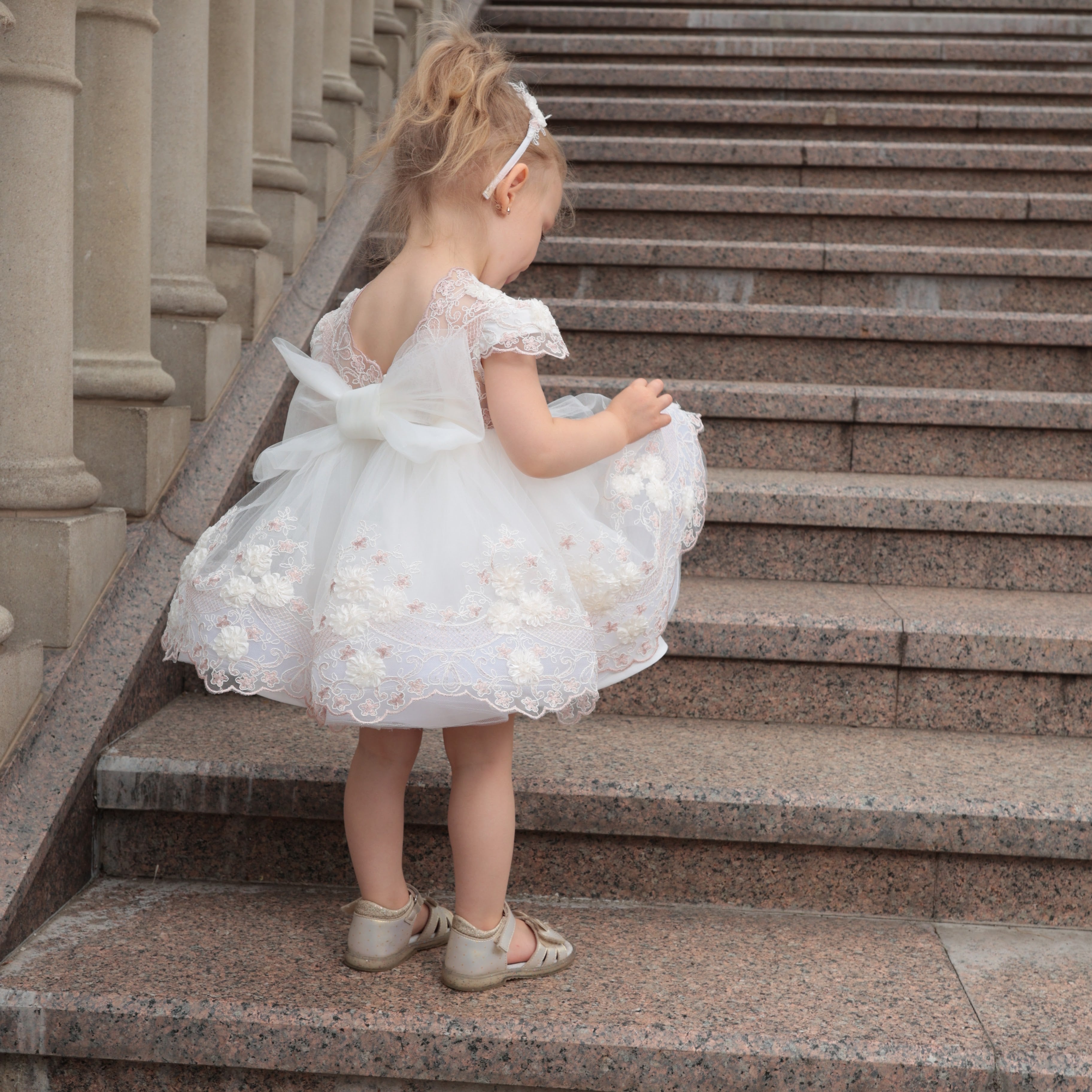 Young girl in a white dress standing on stone steps