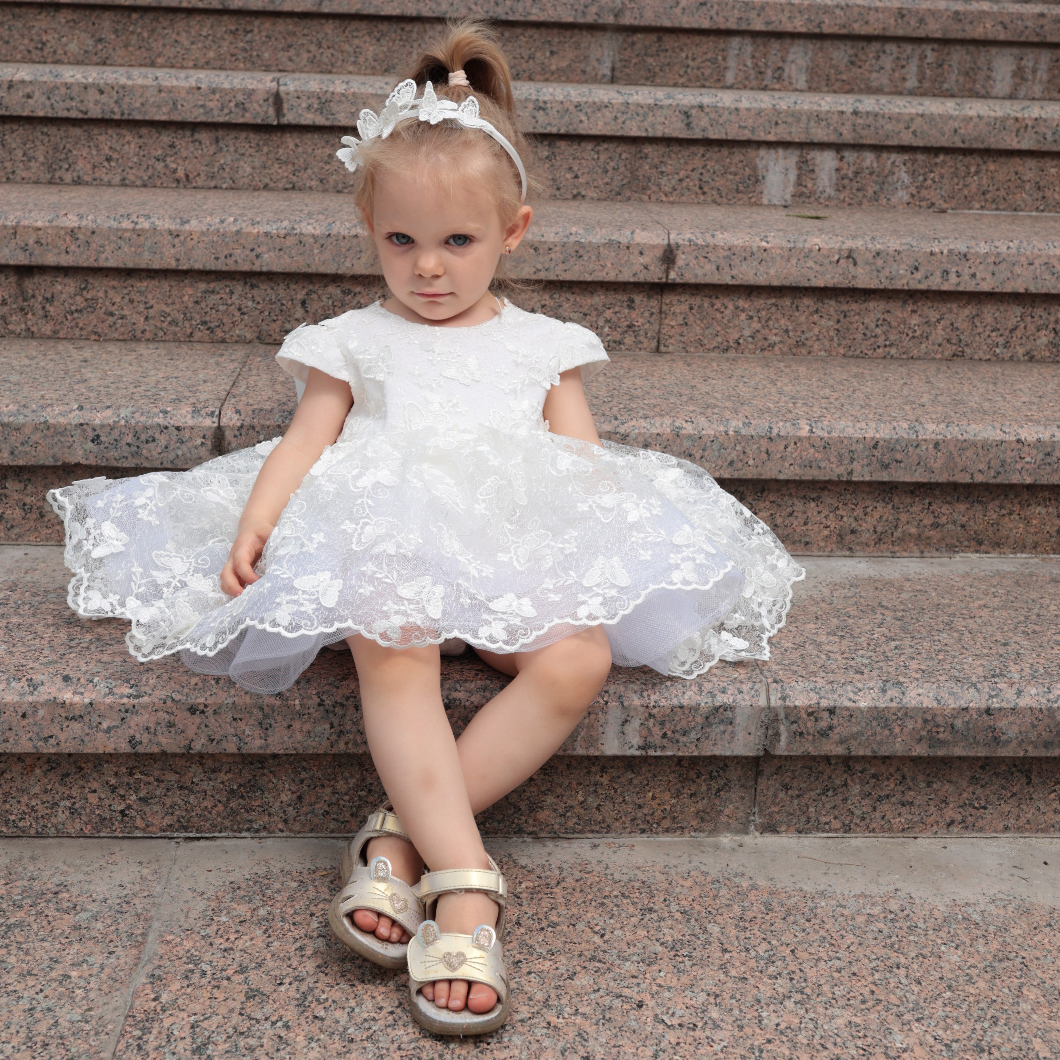 Young girl in a white dress sitting on stone steps