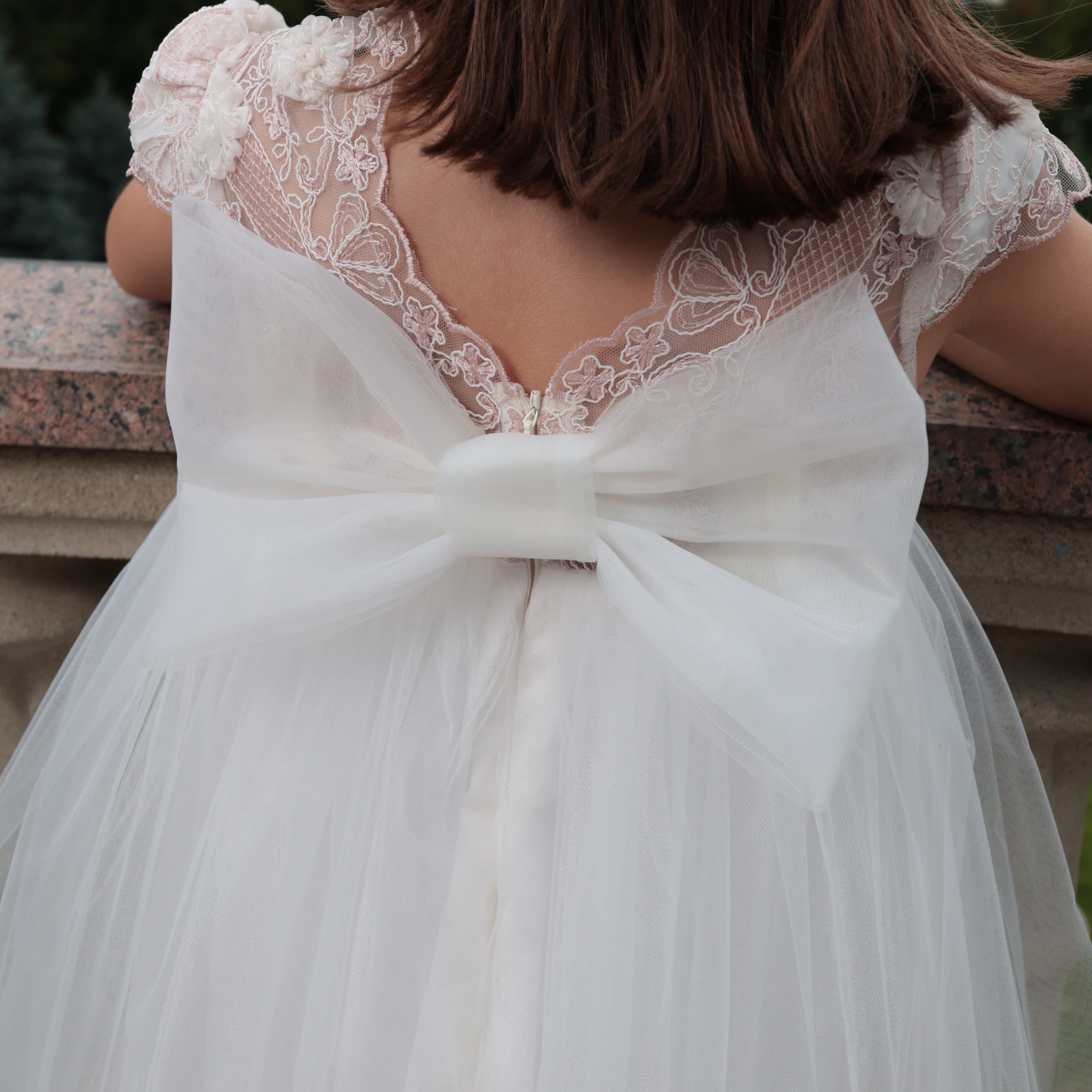 White lace dress with a large bow on the back, worn by a person.
