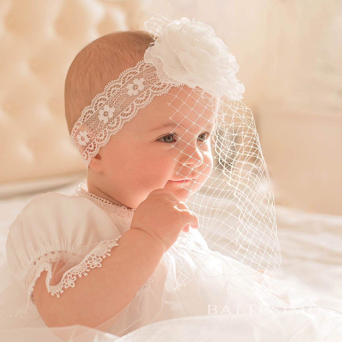 Baby wearing a lbaby headband and veil against a soft background