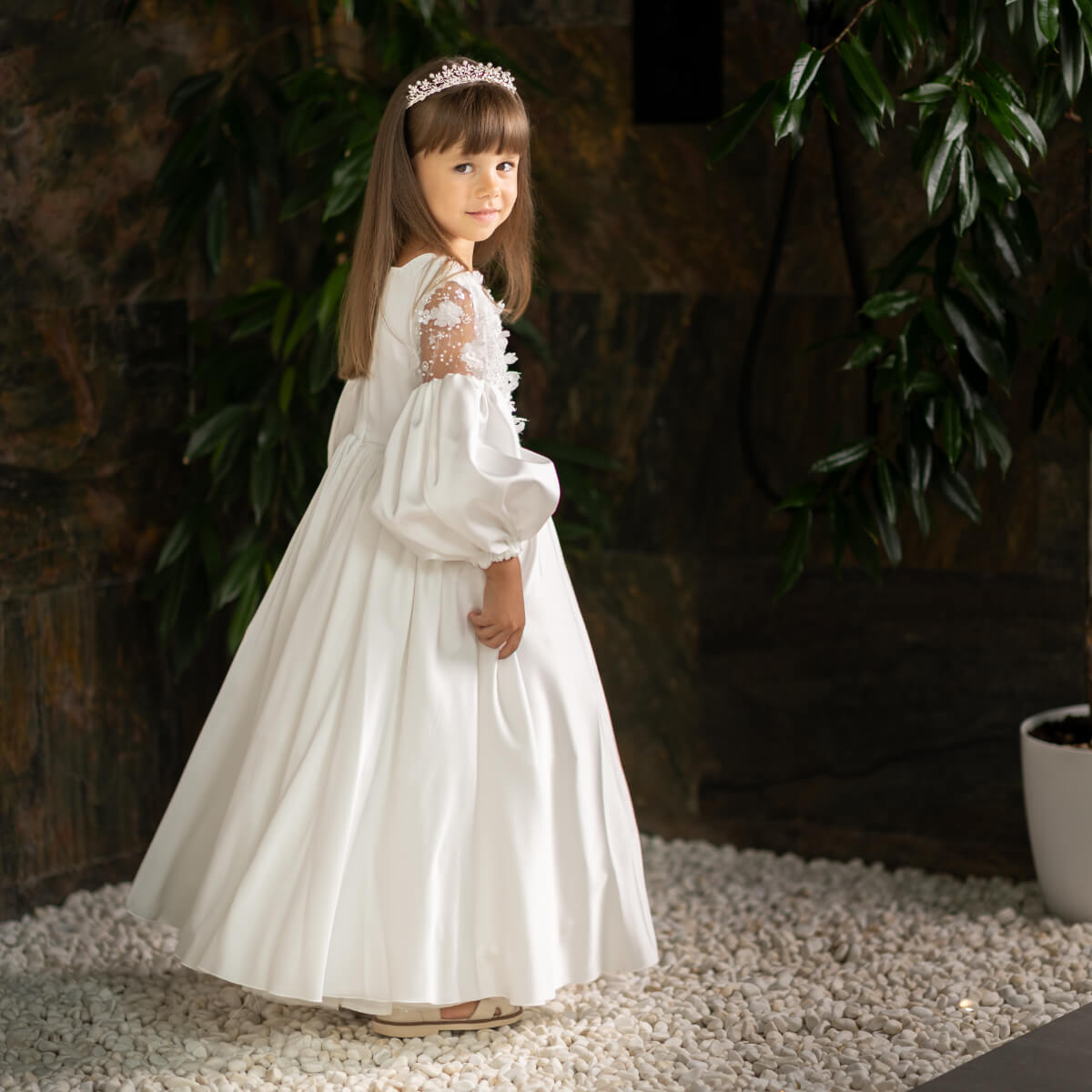 Young girl in a Silk First Communion Dress standing outdoors with greenery in the background