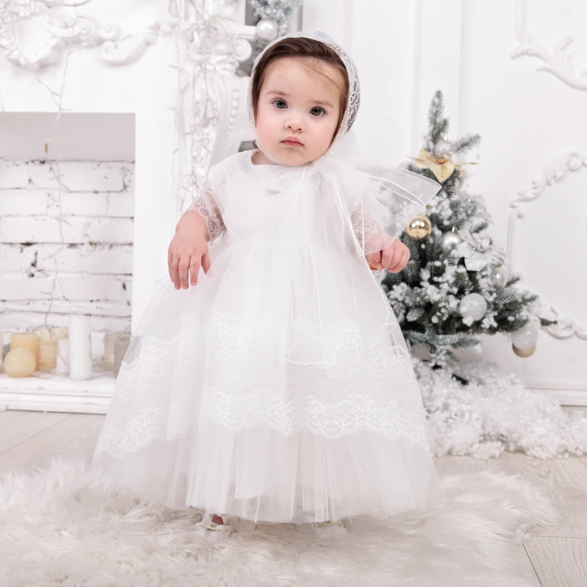 Baby in a Baptism Dress with Train with a Christmas tree in the background