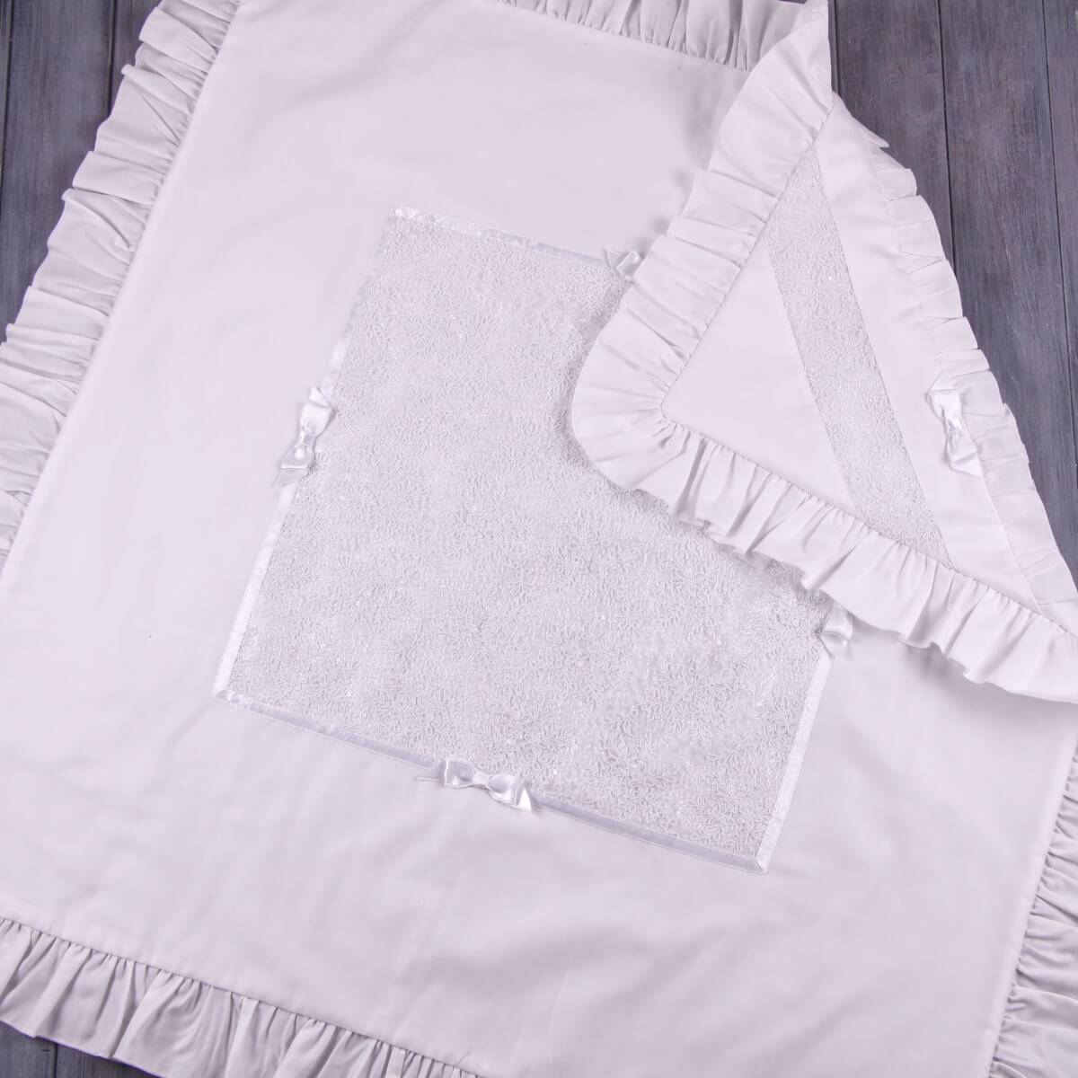 Baptism Blanket in Silk with ruffled edges on a wooden surface