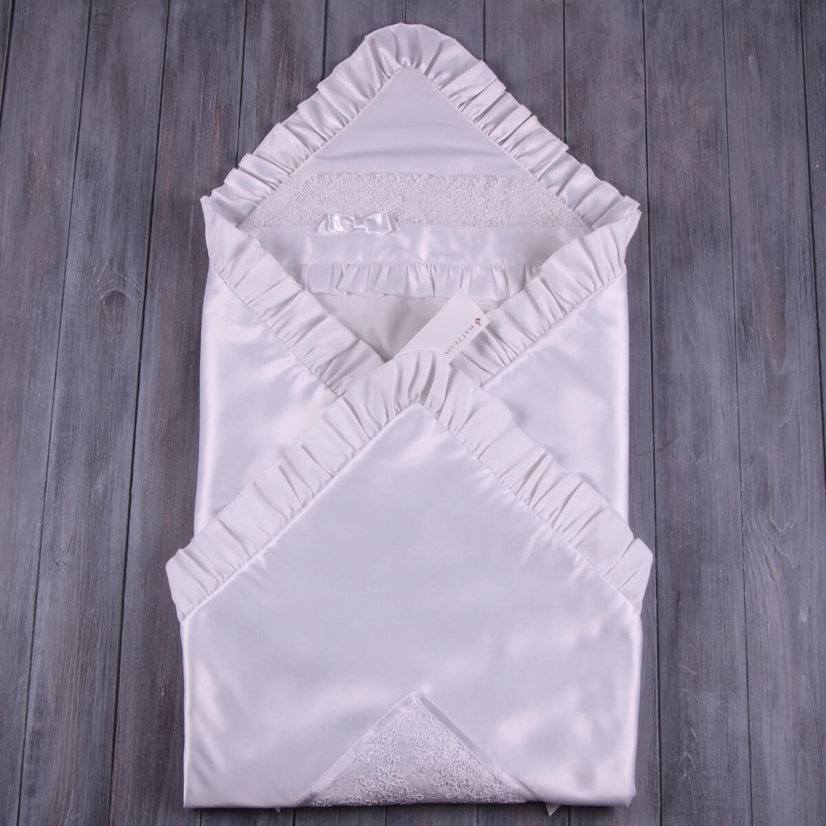 Folded Baptism Blanket in Silk on a wooden surface