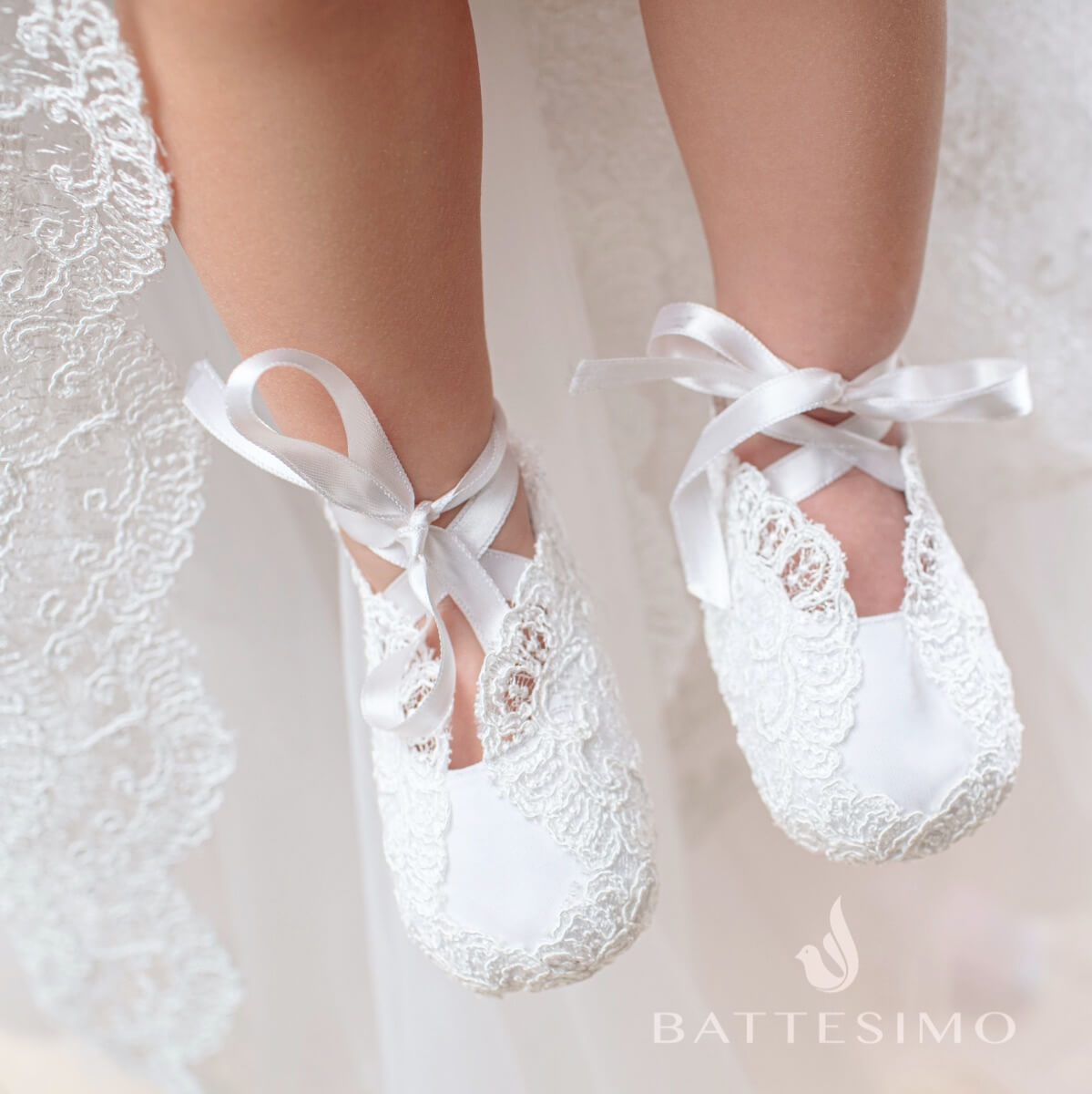Christening Booties s with ribbons on a soft background, featuring the Battesimo brand.