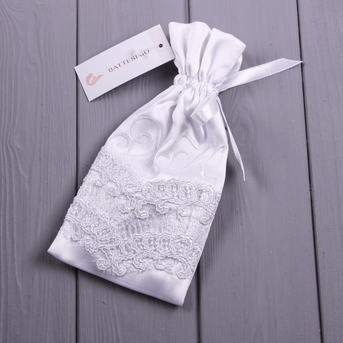 Baby Keepsake Pouch with drawstring on a gray wooden surface, featuring a brand tag.