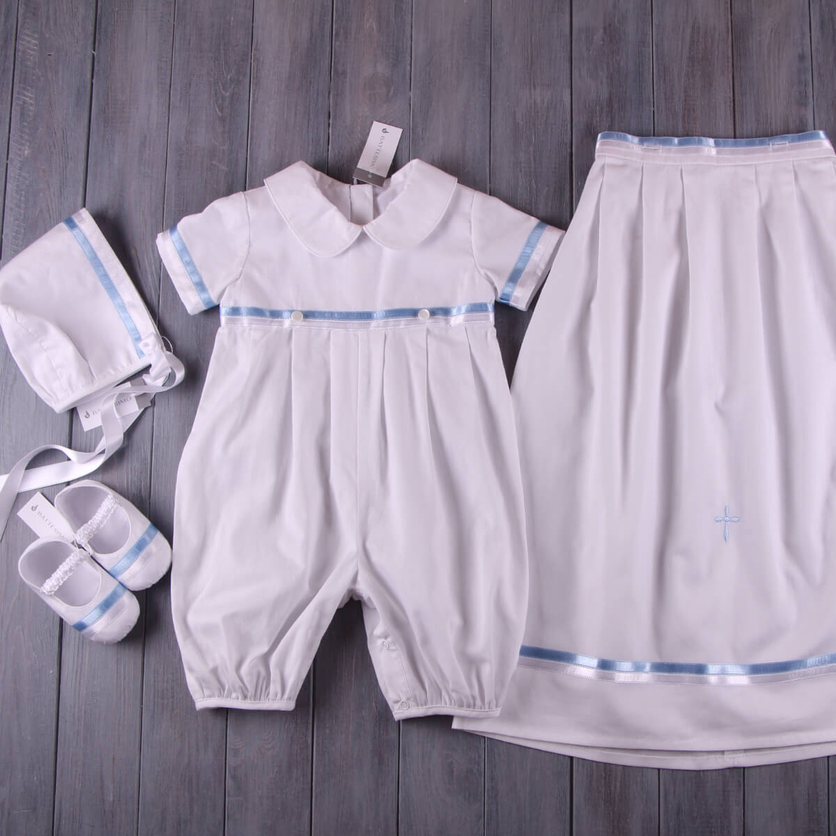 Baptism Outfit for Boys with romper, pants, shoes, and hat on a wooden surface