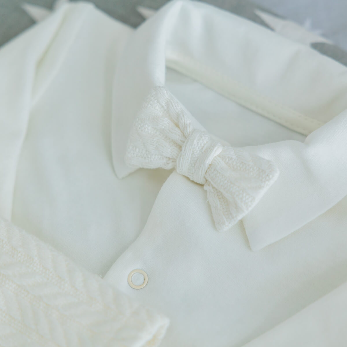 Close-up of a Newborn Coming Home Knit Set  with a bow tie on a neutral background