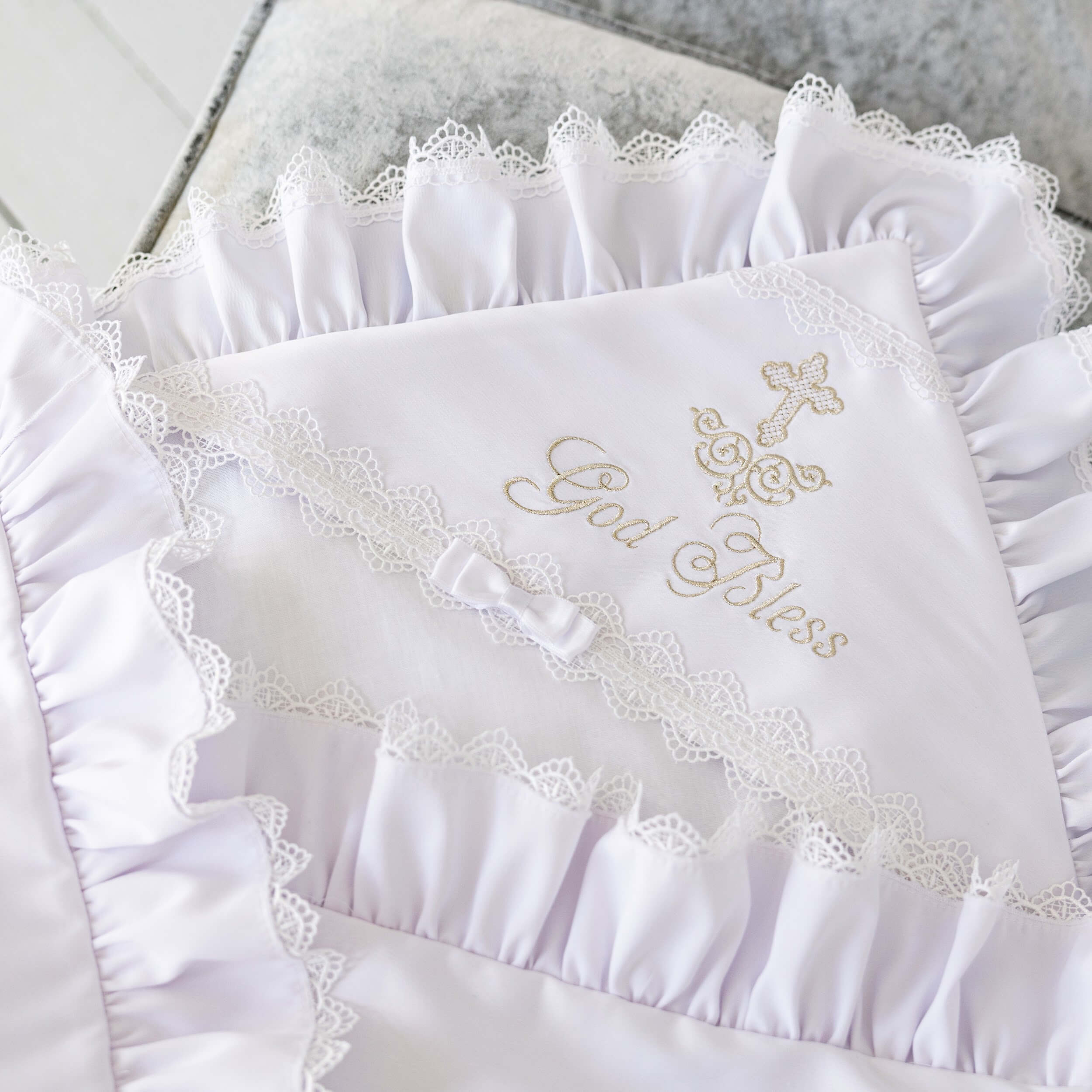 White embroidered baptism blanket with 'God Bless' text on a textured surface