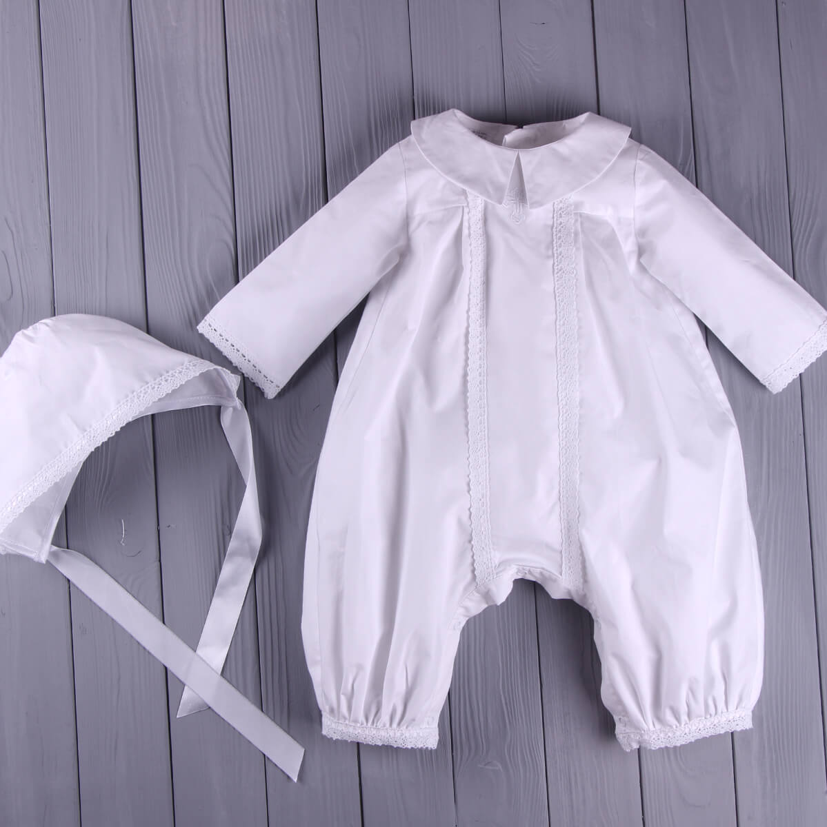 christening outfit for boys with bonnet on a wooden surface