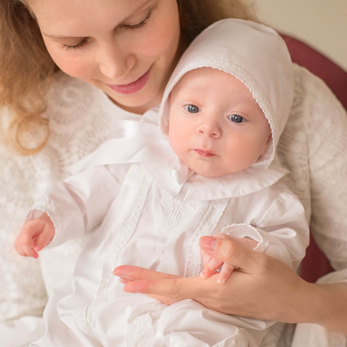 Woman holding a baby wrapped in christening outfit for boys