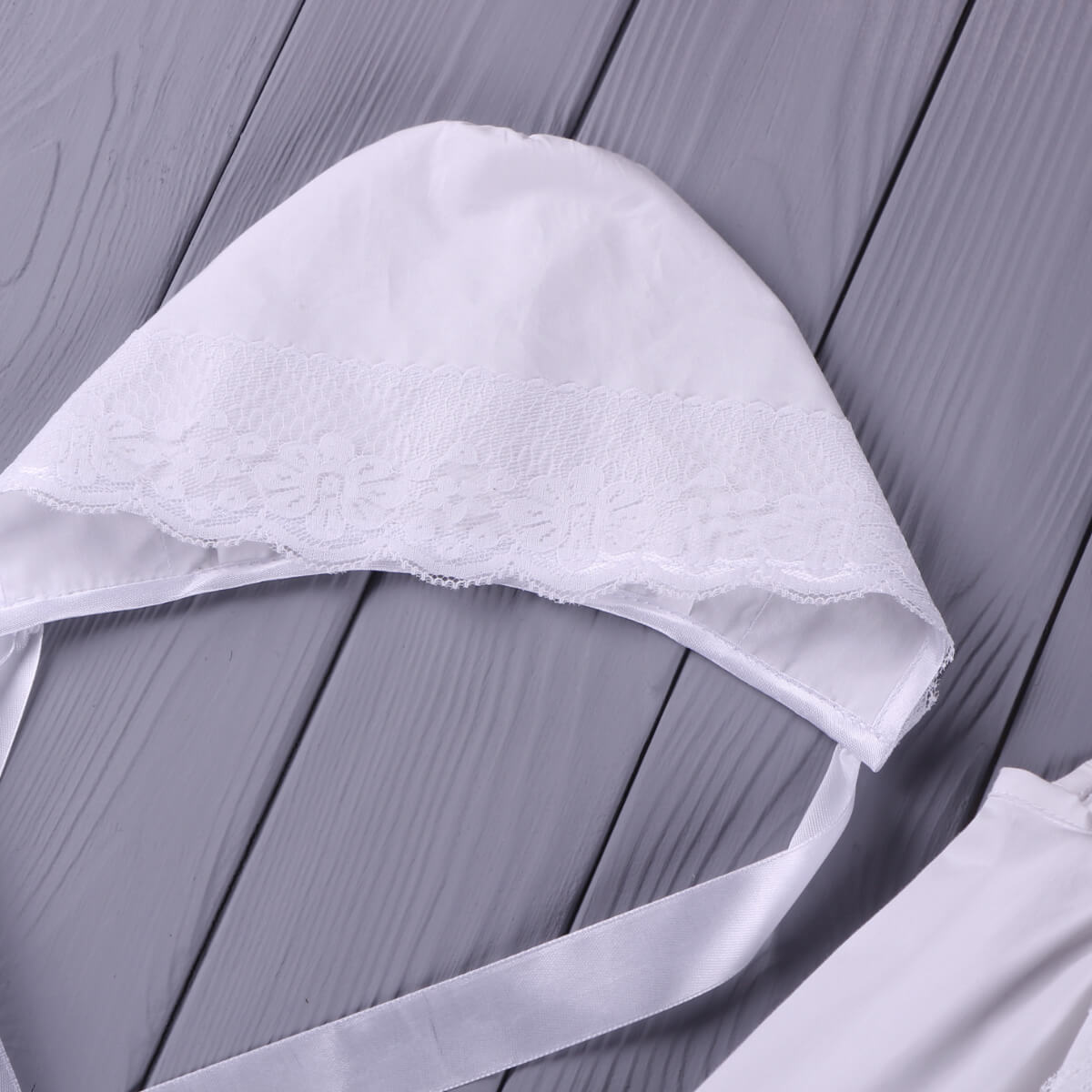 White lace bonnet , as a part of Summer Baptism Dress  on a gray wooden surface