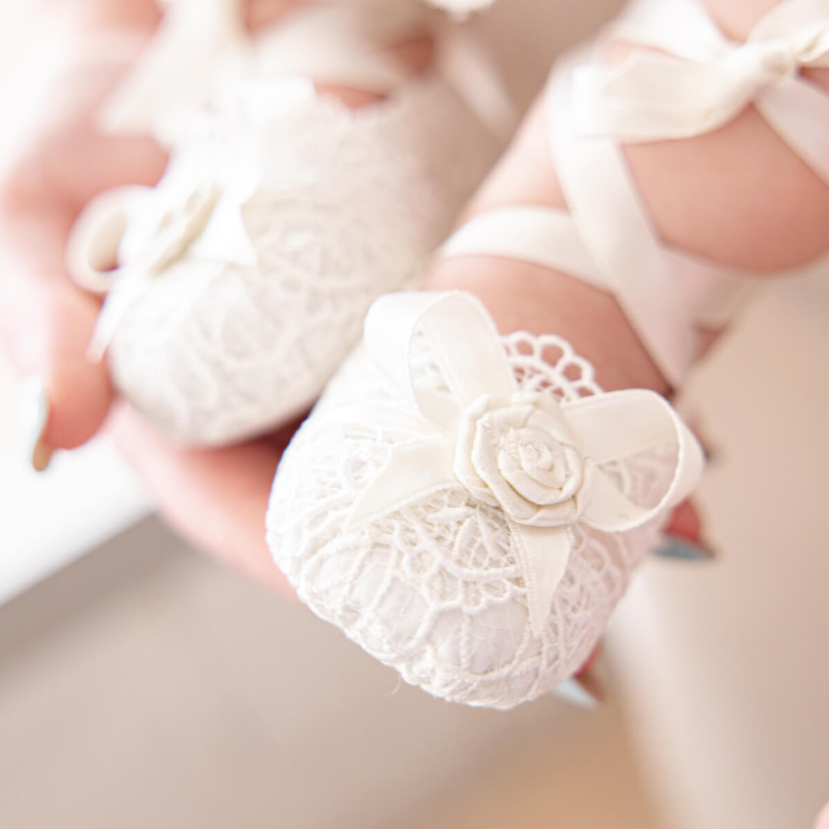 Christening Booties with a floral design held by hands.