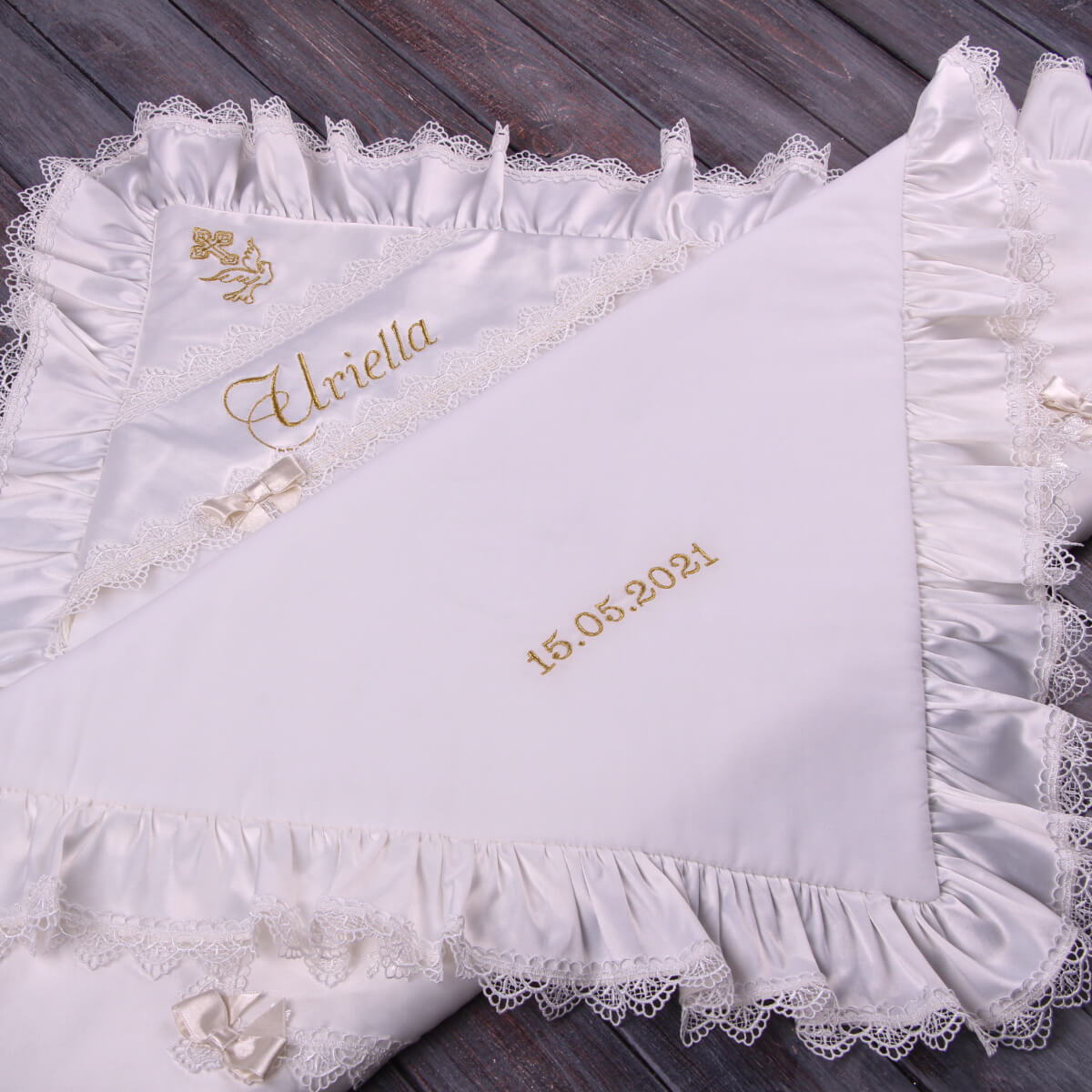 White embroidered blanket with lace trim and personalized text on a wooden surface