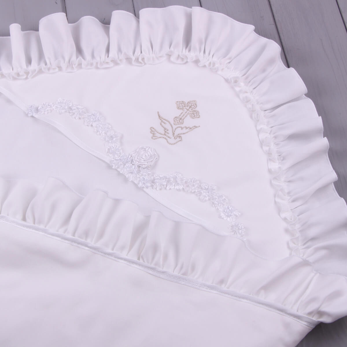 White ruffled christening blanket with floral design on a gray background