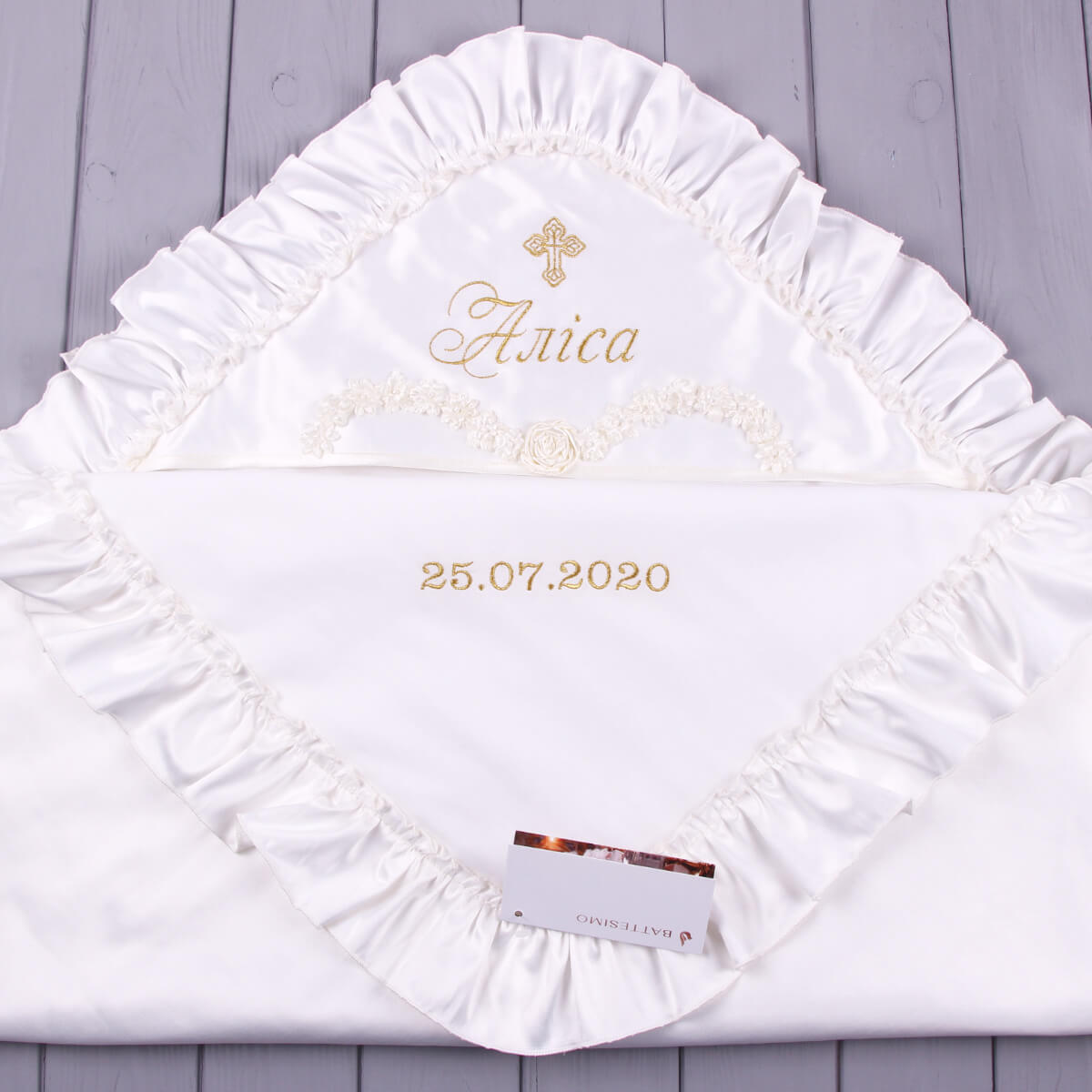 White ruffled christening blanket with decorative edge on a wooden surface