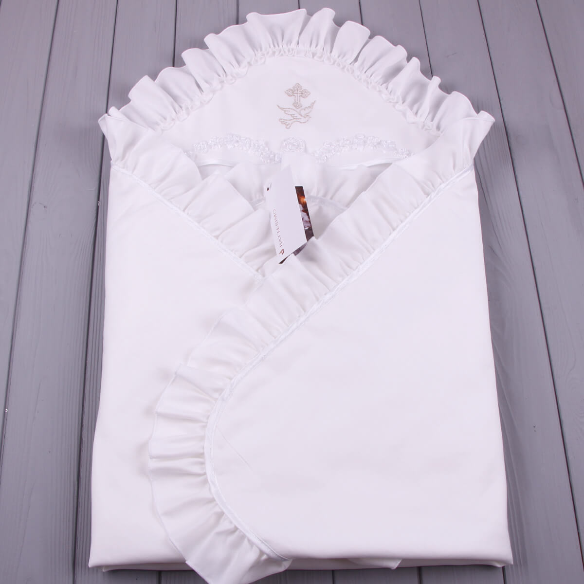 White ruffled christening blanket on a gray wooden surface