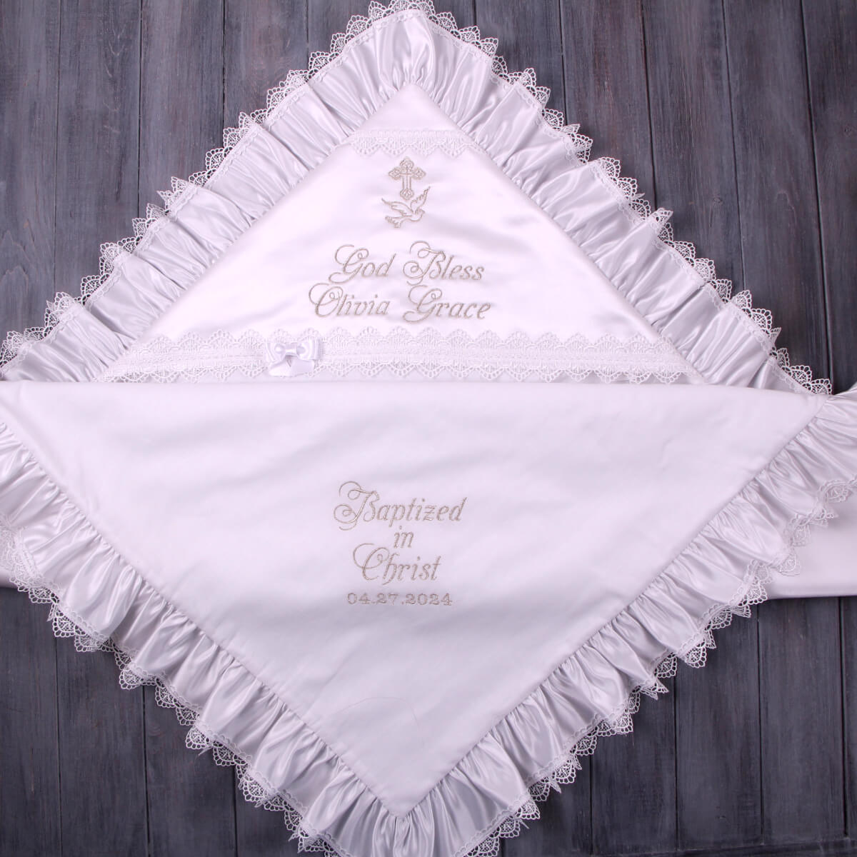 White embroidered baby blanket with personalized text on a wooden background