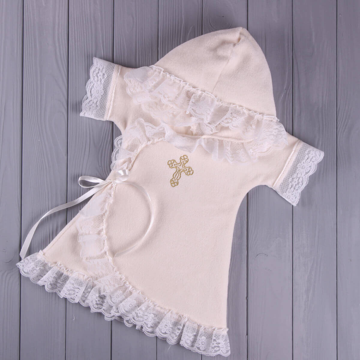 Baptism Gown and a gold cross on a wooden surface