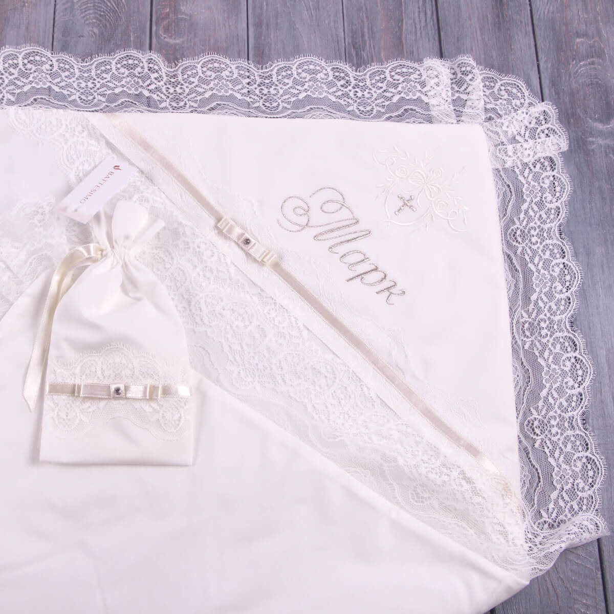 White lace christening blanket with 'Marie' embroidered on a wooden surface