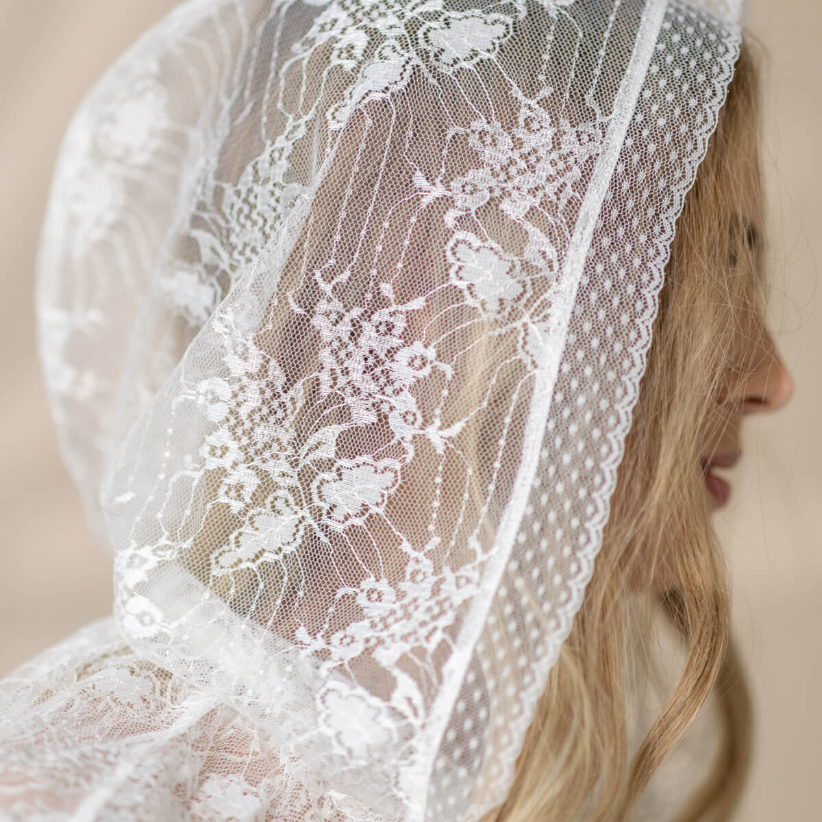 Close-up of a  Lace Hooded Veil worn by a person with a neutral background