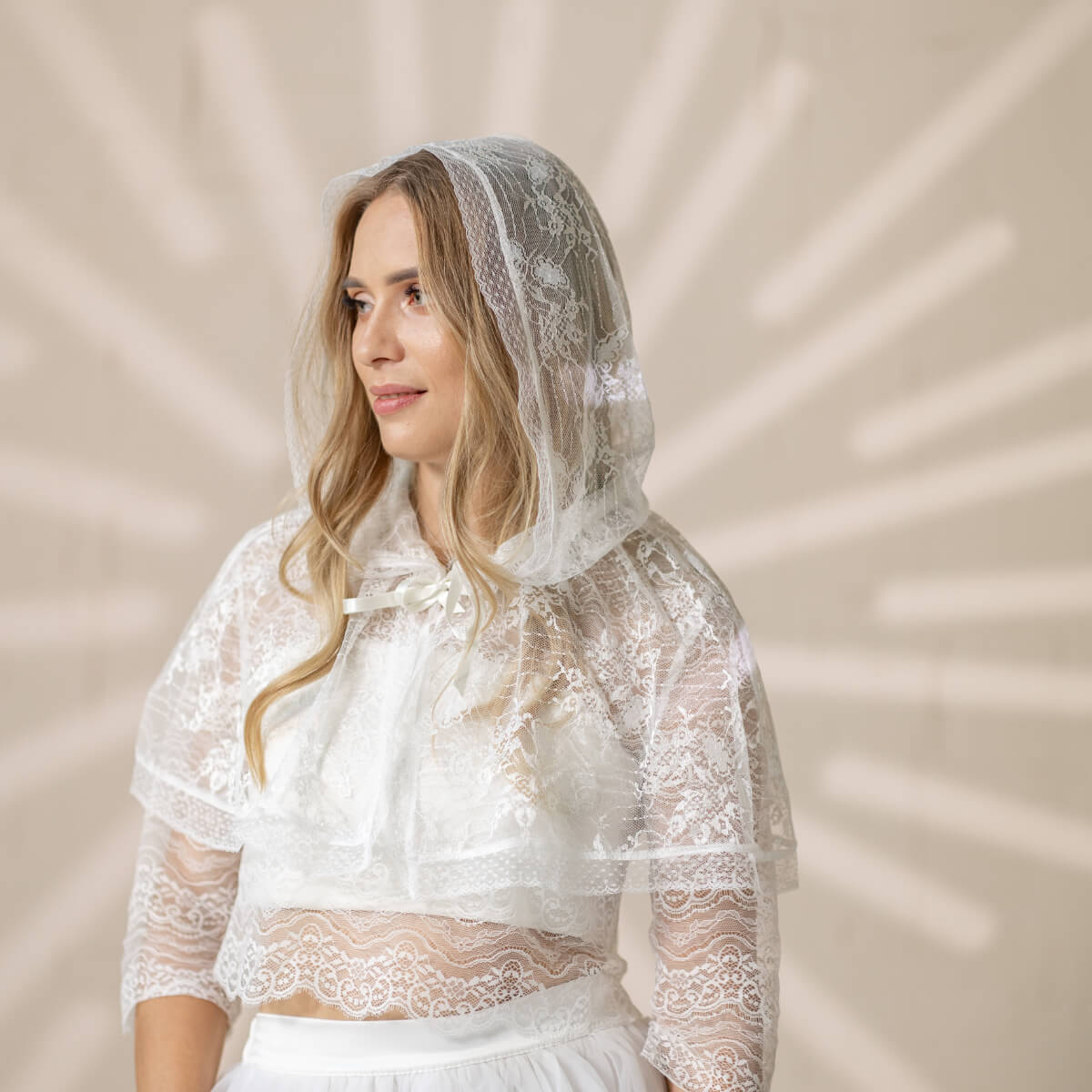 Woman wearing a Lace Hooded Veil against a beige background