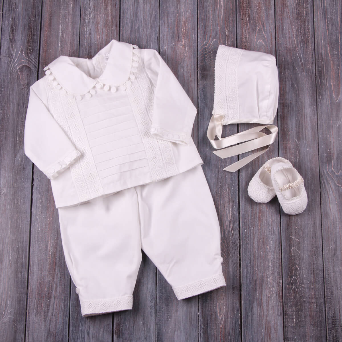 White baby outfit with shirt, pants, Boy Baptism Hat and shoes on a wooden surface